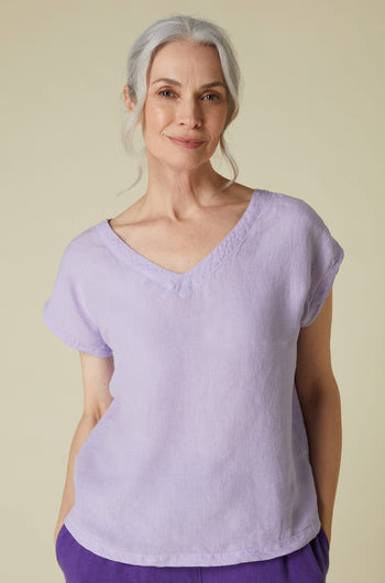 An older woman with gray hair wearing a lightweight, Organza Linen reversible top and smiling at the camera.