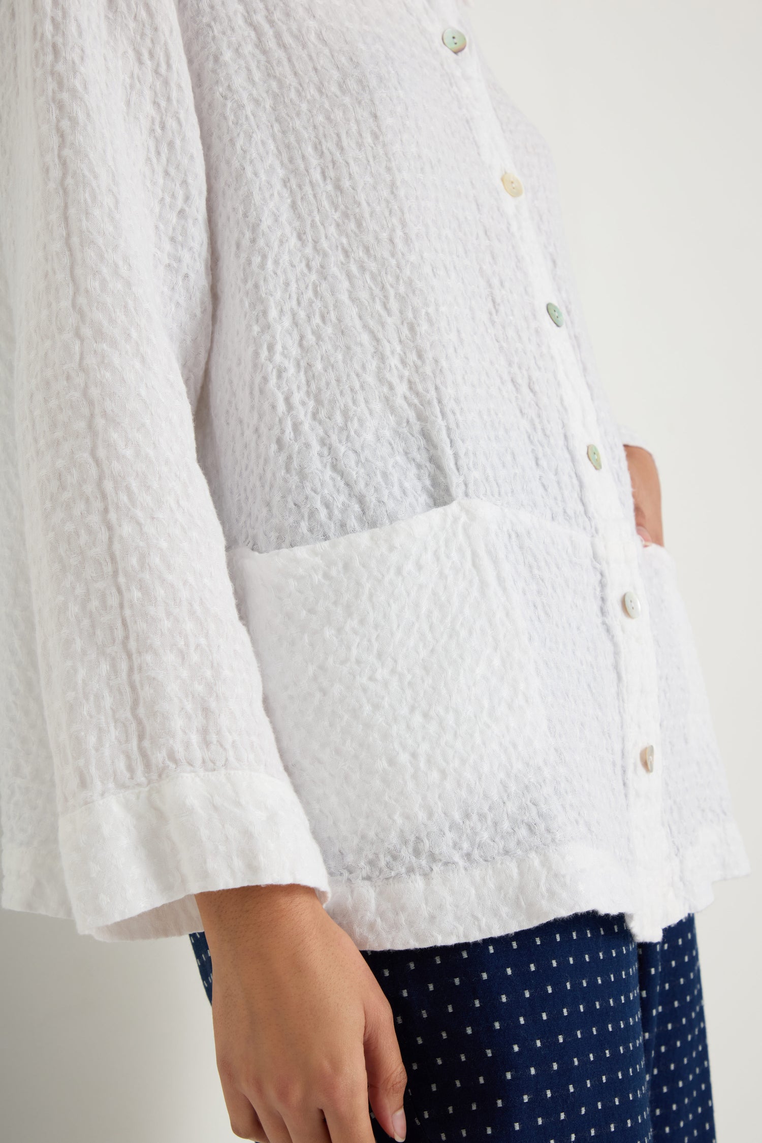 A person wears the Waffle Linen Pocket Shirt with a boxy fit and large pockets, paired with dark blue polka dot pants—an ideal combination for breathable layering.
