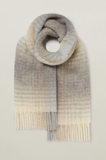 The Soft Check Scarf is a wool blend with a gentle gradient pattern in multicolored hues, fringed ends, and classic check detailing, elegantly showcased against a plain background.