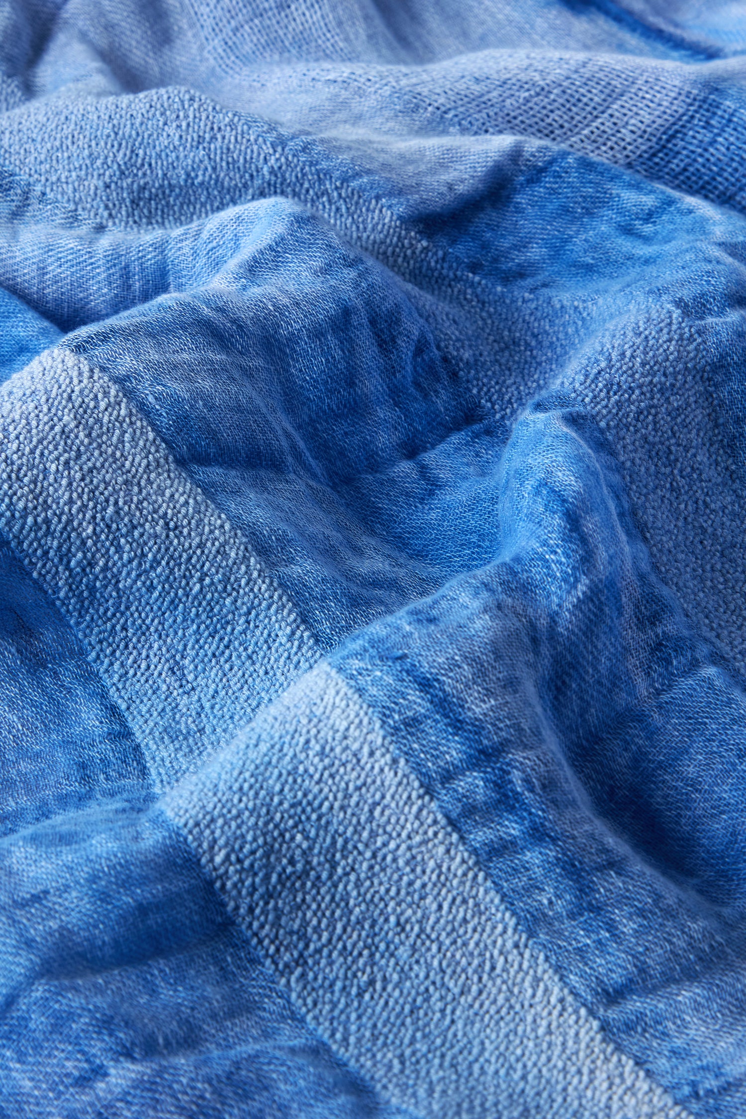 Close-up of the Sky Linen Mix Scarf showcasing a textured, slightly wavy blue cotton fabric with visible fibers, evoking a cozy feel.