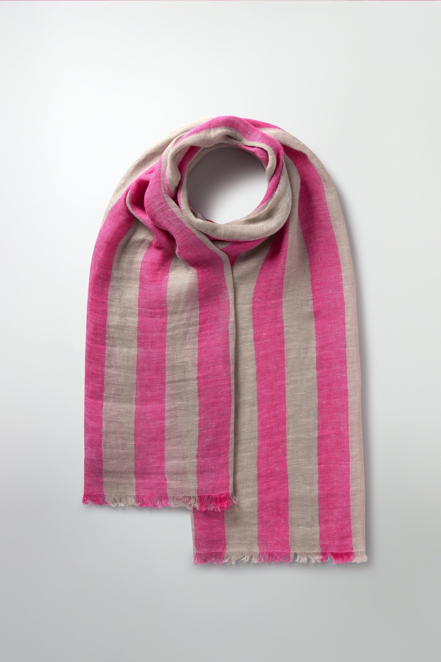 The Linen Stripe Scarf with wide pink and beige bands, draped in a circular shape on a light background, is the ideal spring or summer accessory.