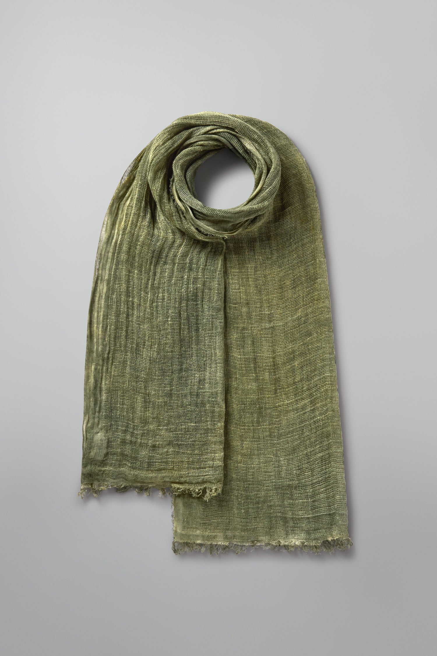 The Woven Linen Scarf, crafted from 100% linen, displays its textured elegance and raw-edge finish against a plain gray background.