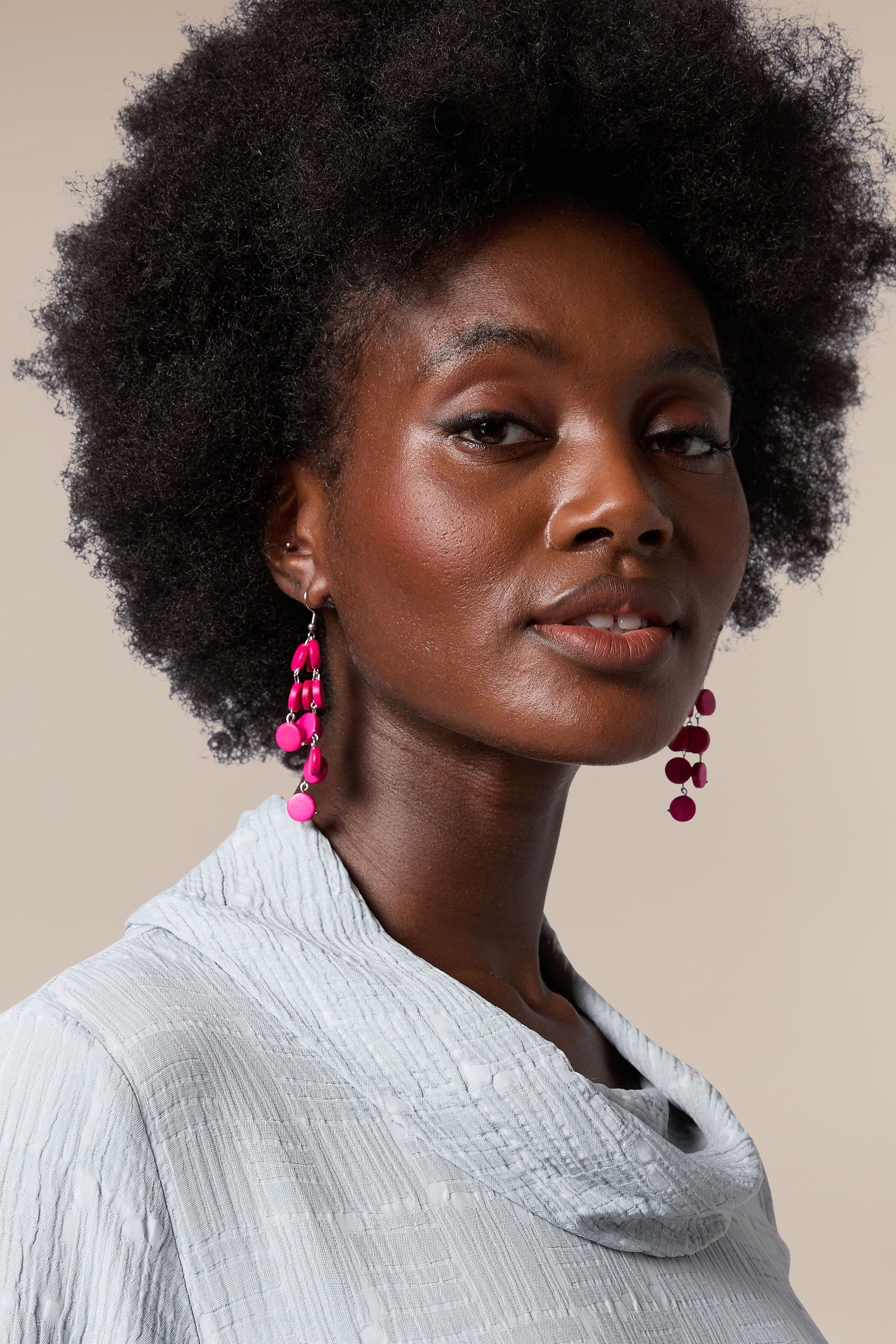 A black woman wearing a grey top and Cascade earrings handcrafted by local artisans.