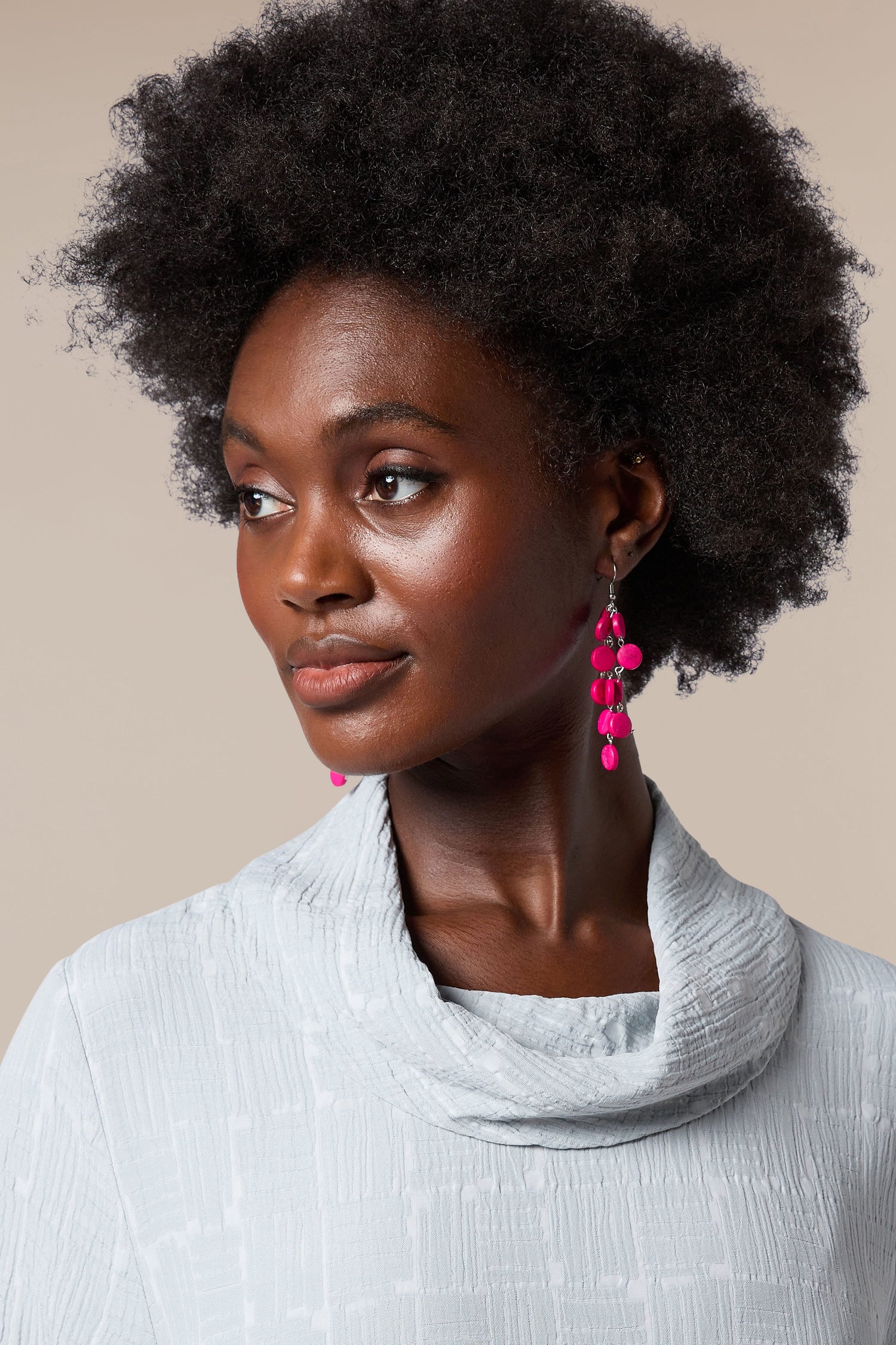 A black woman wearing a grey sweater and Cascade Earrings handcrafted by local artisans.