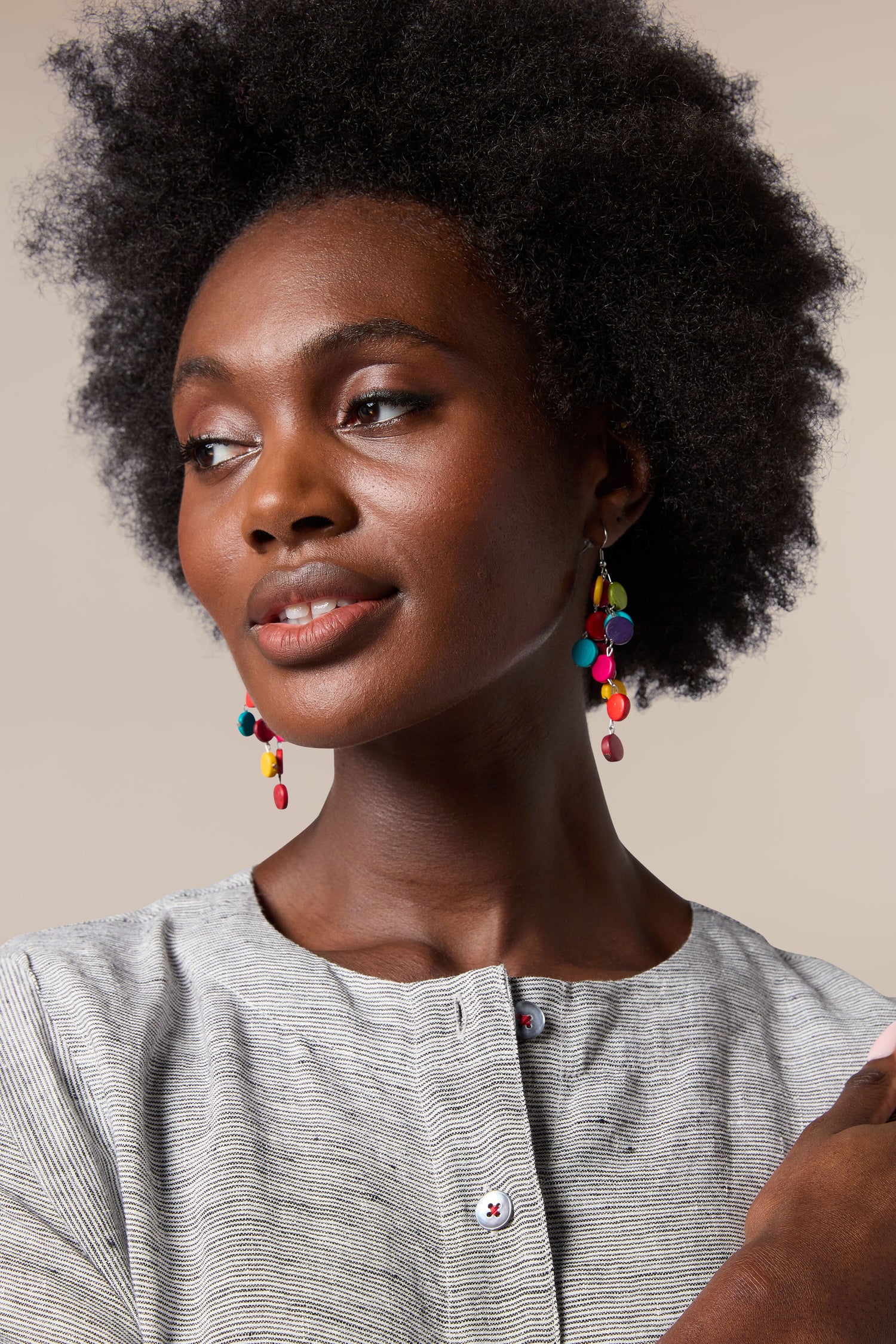 A black woman with afro hair showcasing her vibrant and handcrafted Cascade Earrings from local artisans.