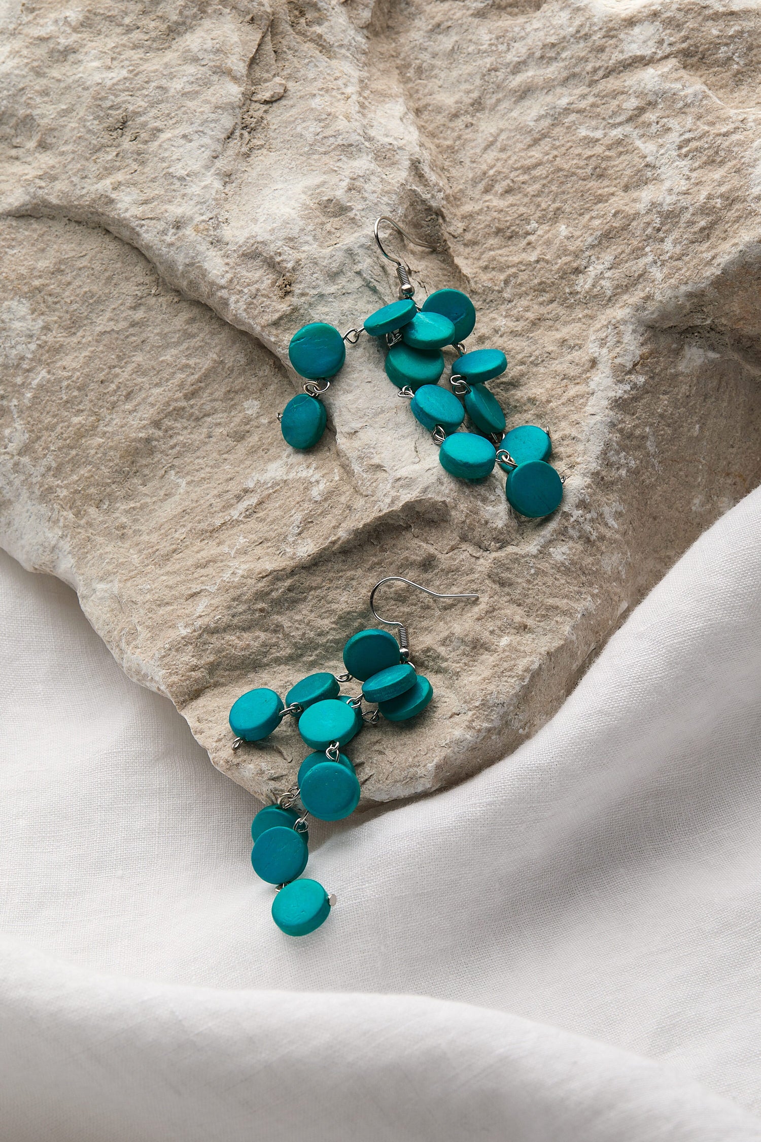 Cascade earrings handcrafted by local artisans, laying on top of a rock.