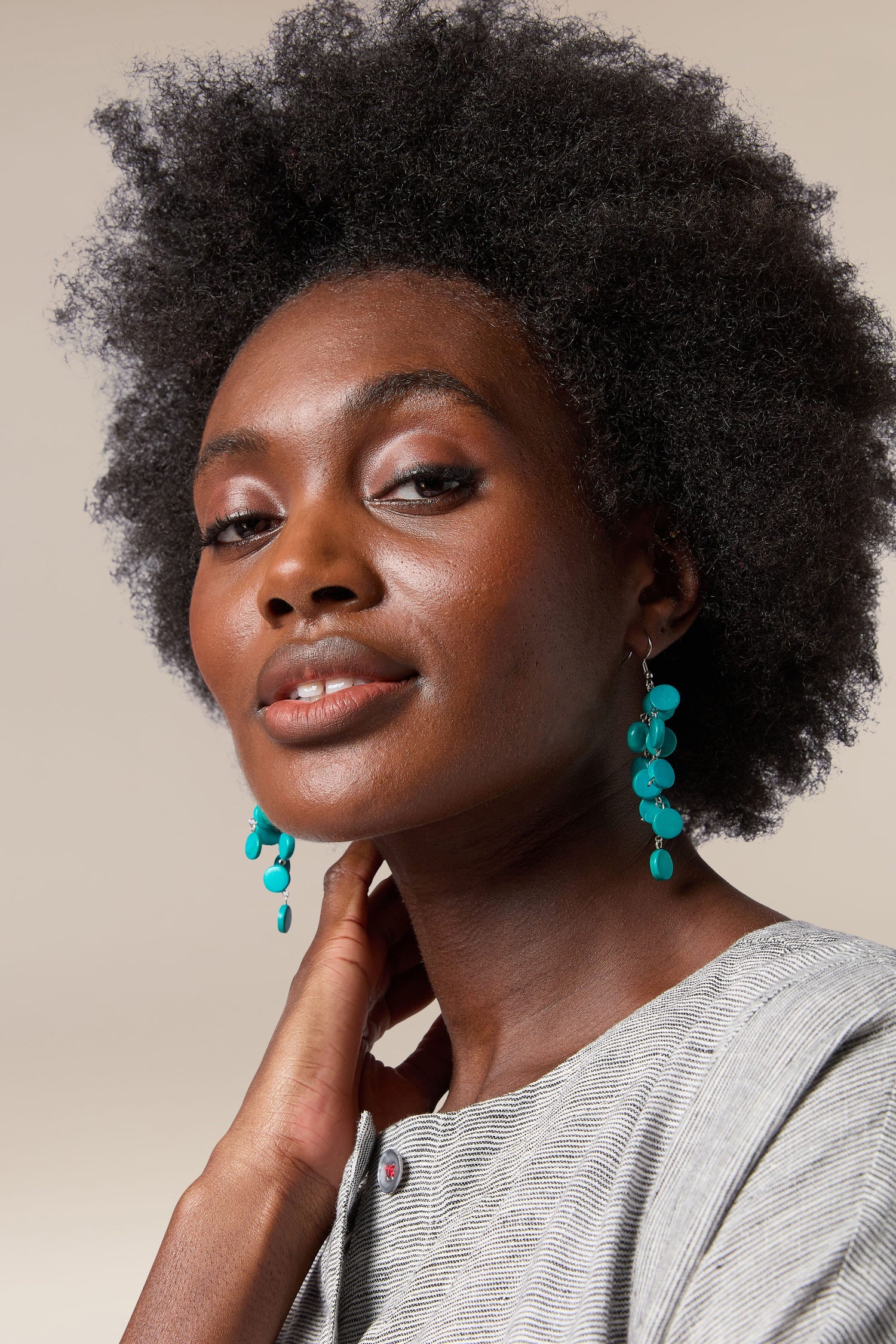 A handcrafted black woman with afro hair wearing Cascade Earrings made by local artisans.