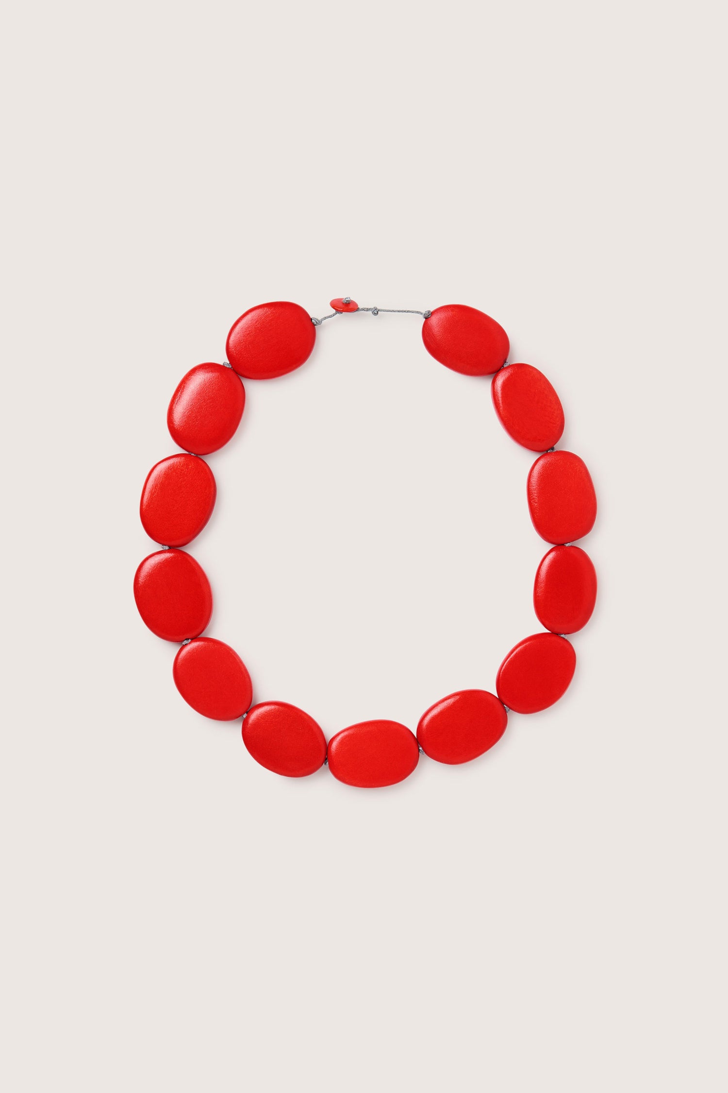 The Short Wooden Pebble Necklace, model LFH2113, features large, glossy red oval beads arranged in a circle on a plain background.