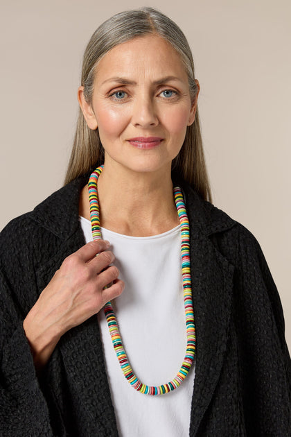 A woman wearing a Long Coco Disc Necklace adorned with vibrant disc beads.