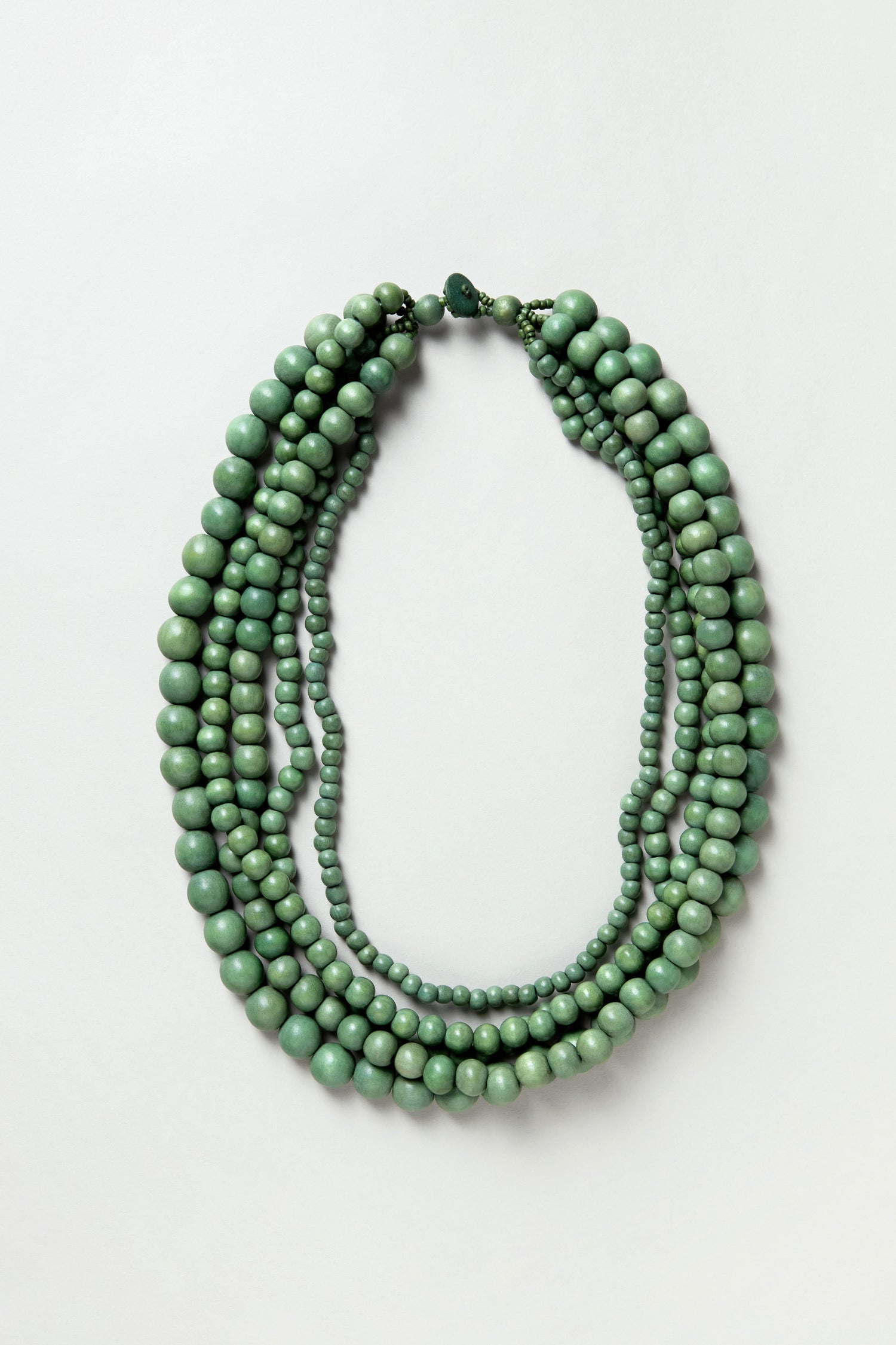 The Statement Bead Necklace features round green sustainable wood beads in assorted sizes, displayed flat on a plain white background.