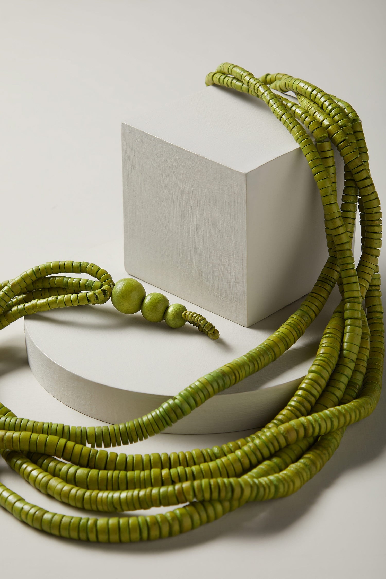 A Coconut Shell Disc Necklace with green coconut shell beads on top of a white surface.