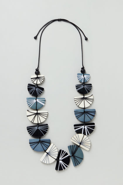 The Fan Necklace (LFHC0324), a blue, black, and white geometric beaded necklace with a cord and bead closure, is displayed on a light background with "Coming Soon" repeatedly overlaid on the image.
