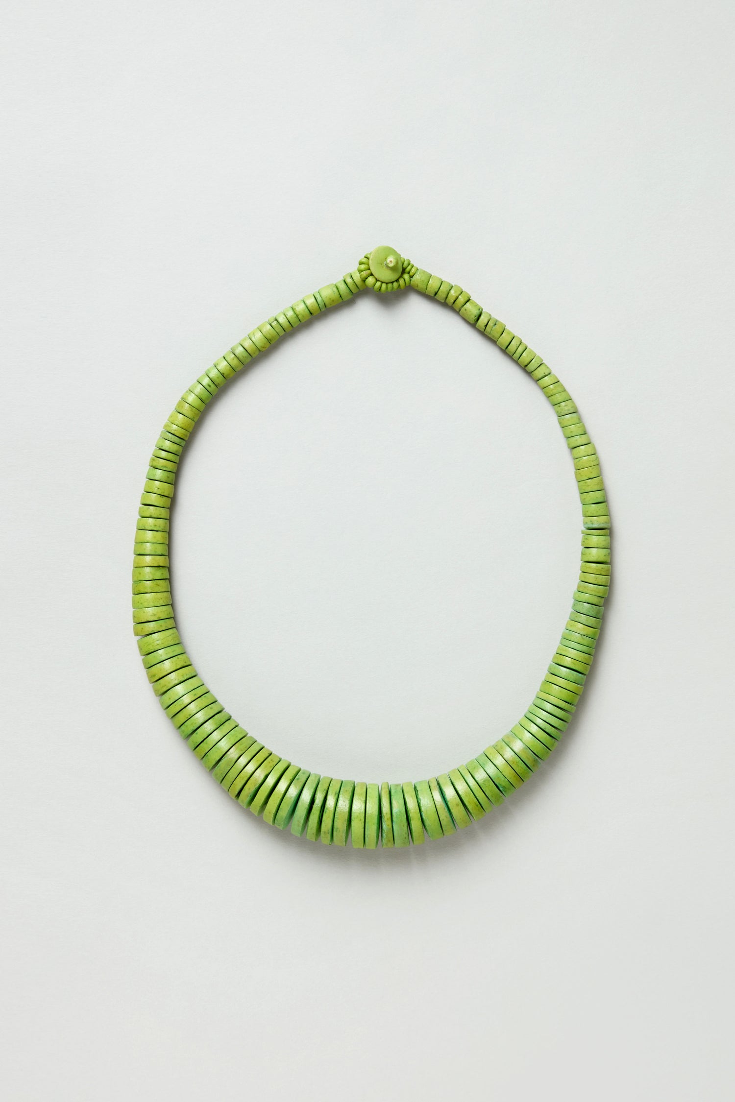 The Graduated Coco Disc Necklace is handcrafted in the Philippines with ethically sourced green beads arranged in a graduated pattern, shown on a plain white background.
