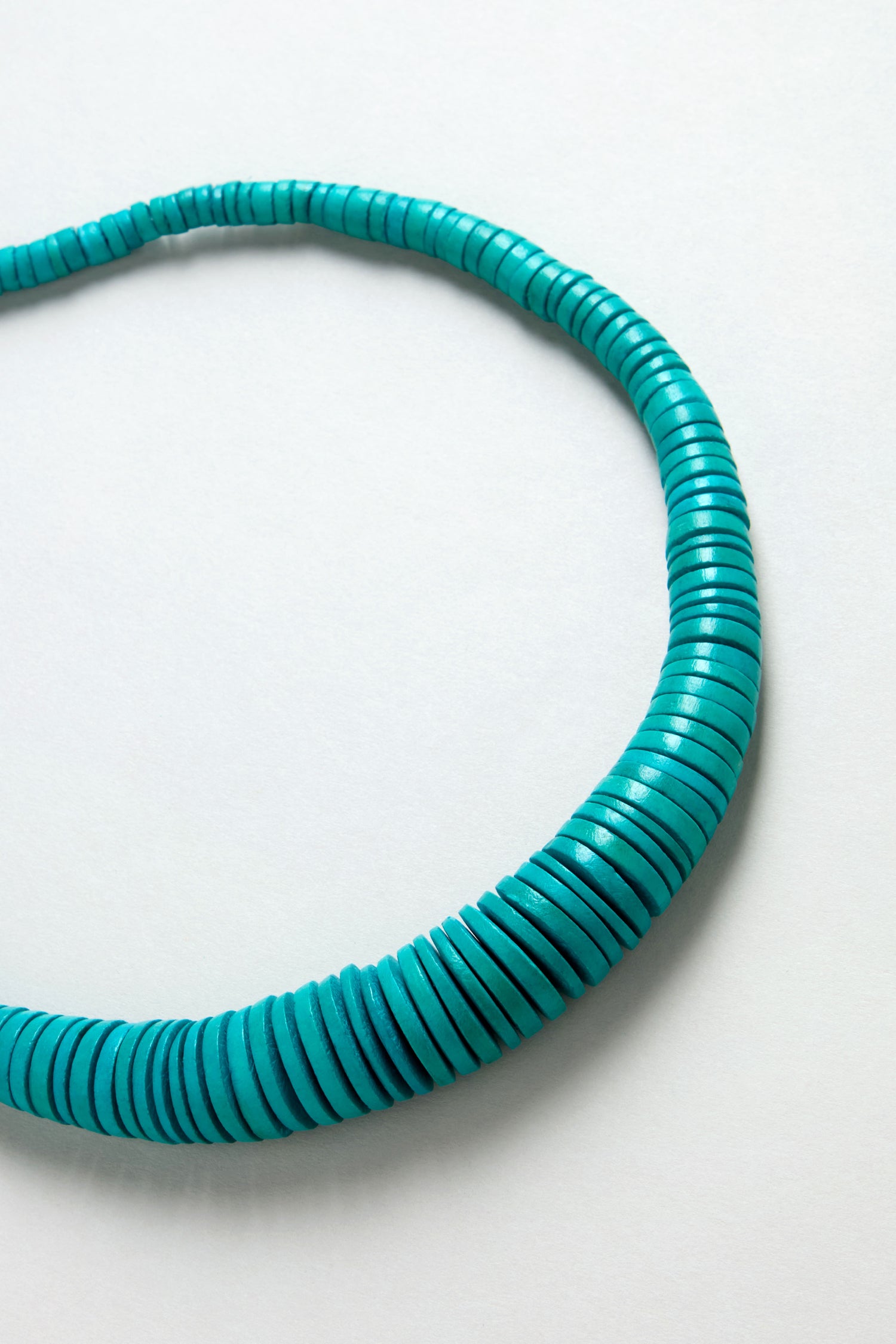 A close-up of the Graduated Coco Disc Necklace, handcrafted in the Philippines from ethically sourced materials, displayed in a partial circle on a plain white background.