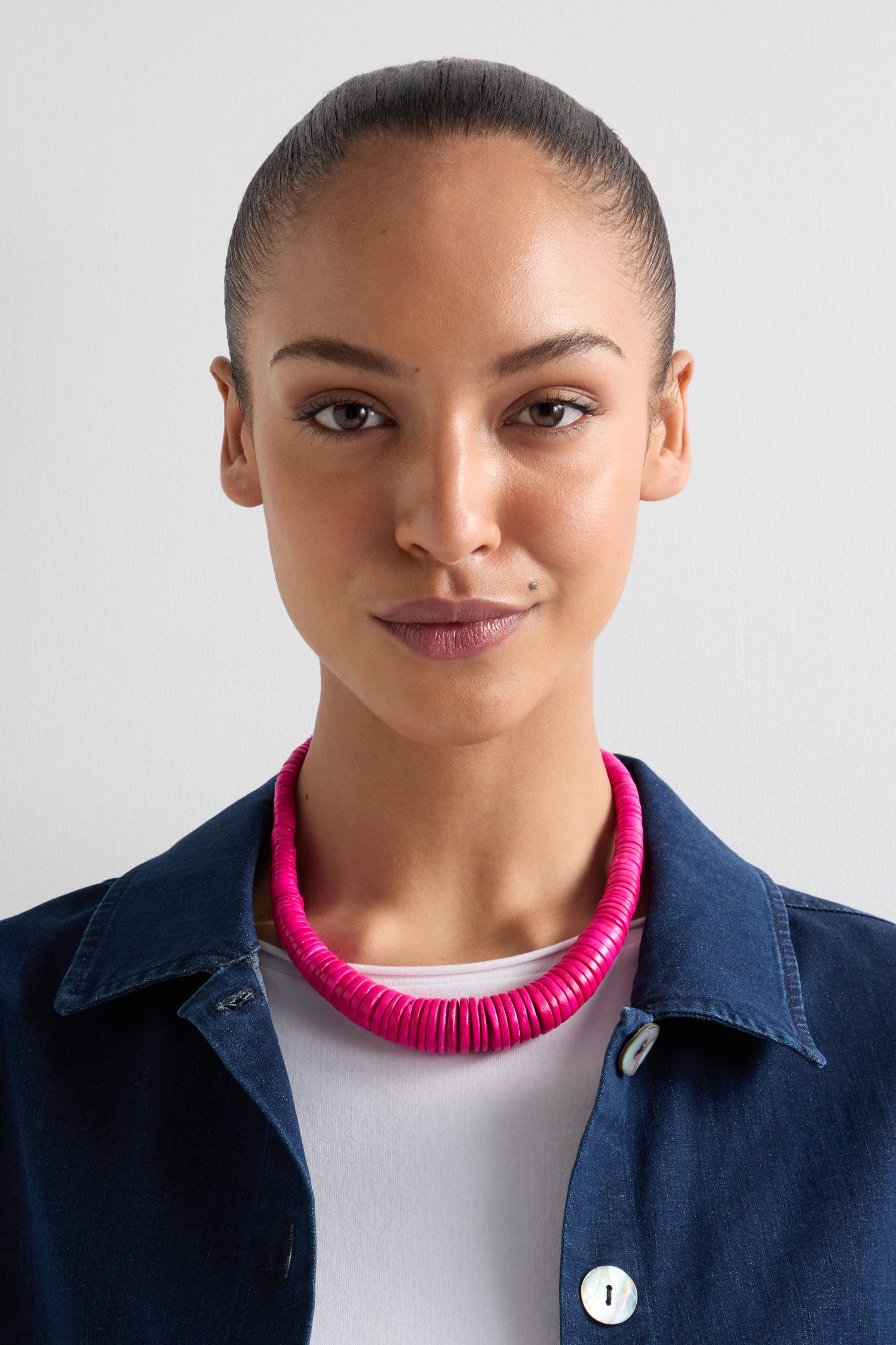 Individual with a neutral expression, in a dark blue jacket over a white shirt, wearing the Graduated Coco Disc Necklace to highlight the artistry of Philippine craftsmanship.