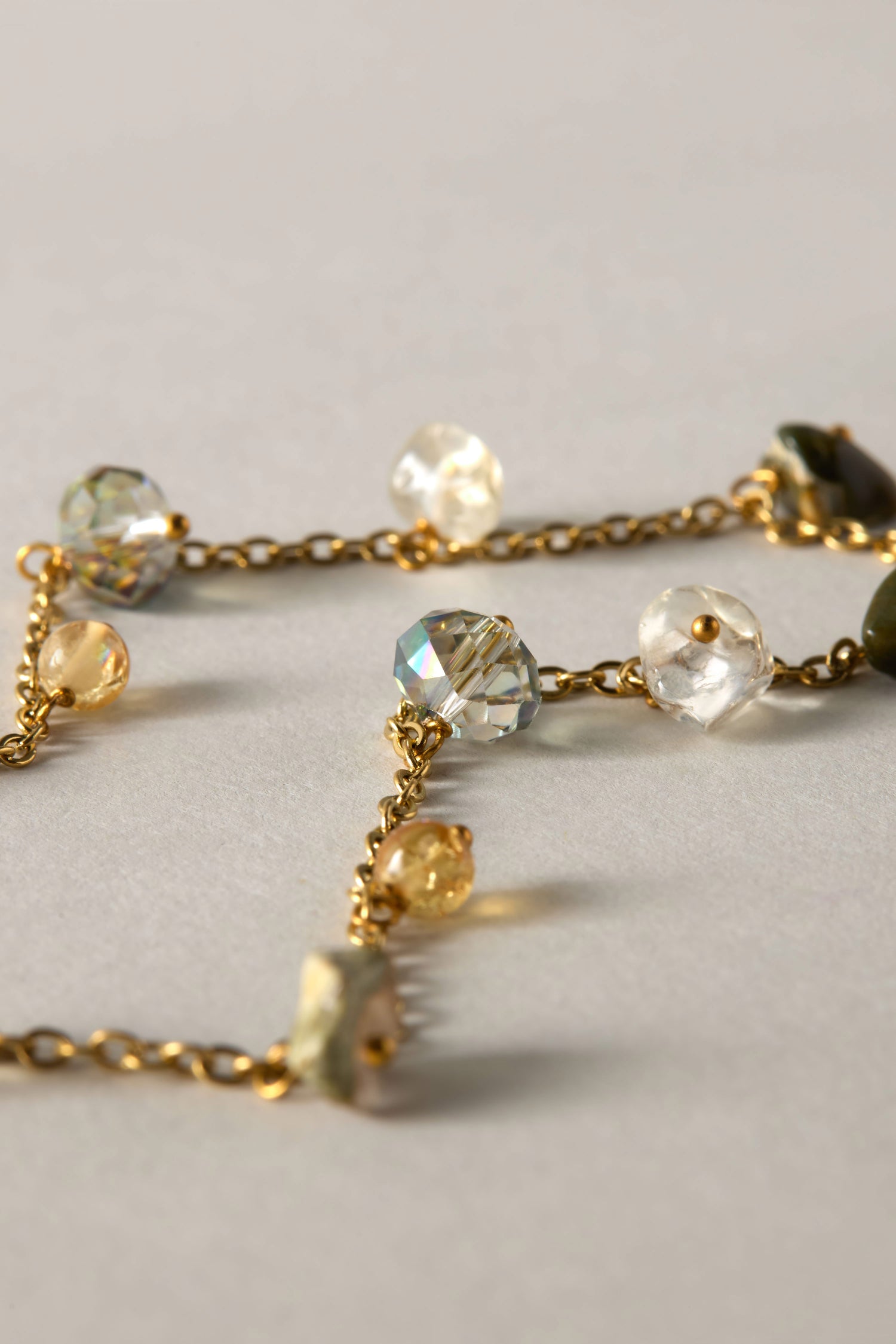 A detailed view of the Citrine and Rhyolite Bead Necklace showcases its gold chain adorned with vibrant semi-precious stones, beautifully arranged on a light background to capture the essence of bohemian jewelry.