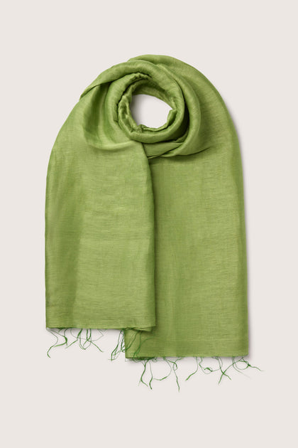 A Soft Linen Scarf with frayed ends, neatly rolled at the top in a circular shape and laid flat on a beige surface.