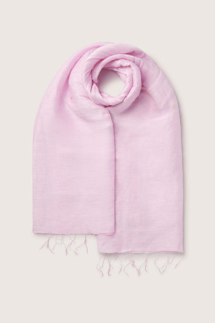 A luxurious linen, light pink Soft Linen Scarf with frayed edges, rolled up and displayed against a plain off-white background, proudly representing fair trade values.