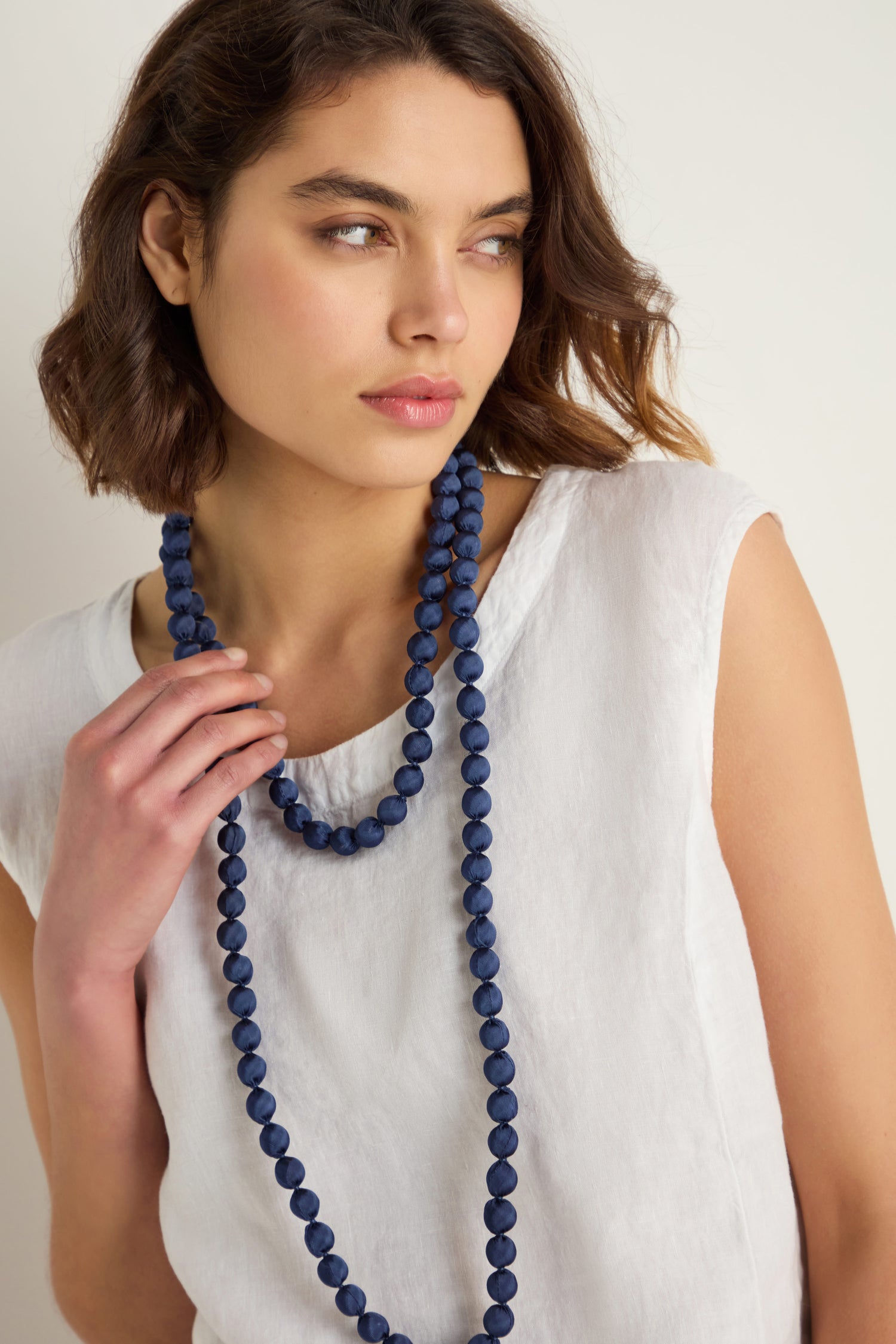 A woman wearing the Handmade Long Silk Spheres Necklace in blue, highlighting artisanal jewelry that is stunning and lightweight.