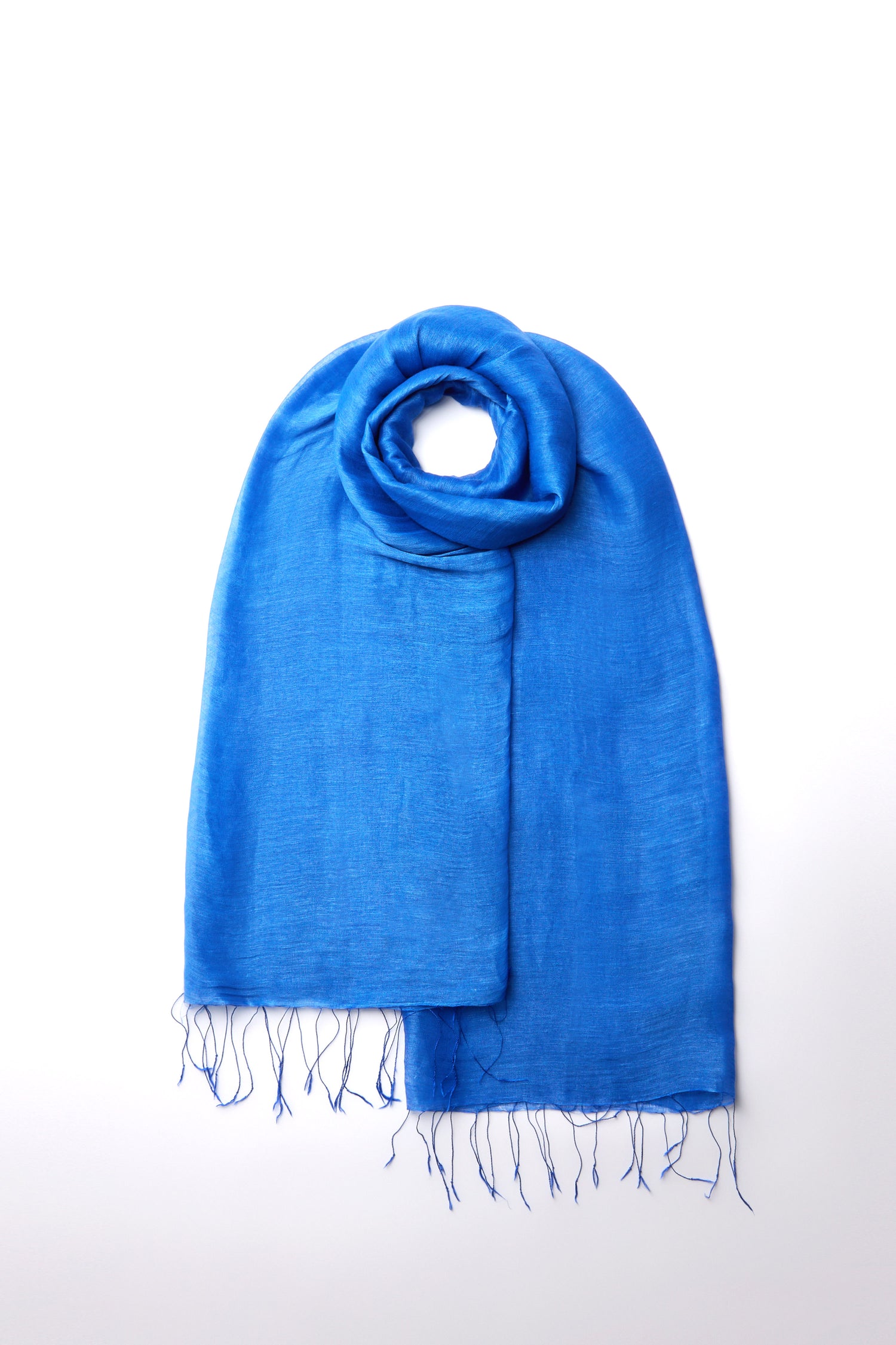 The Soft Linen Fringe Scarf in vibrant blue features fringed edges, presented neatly folded on a white background. It adds bohemian charm and elegance to any versatile wardrobe.