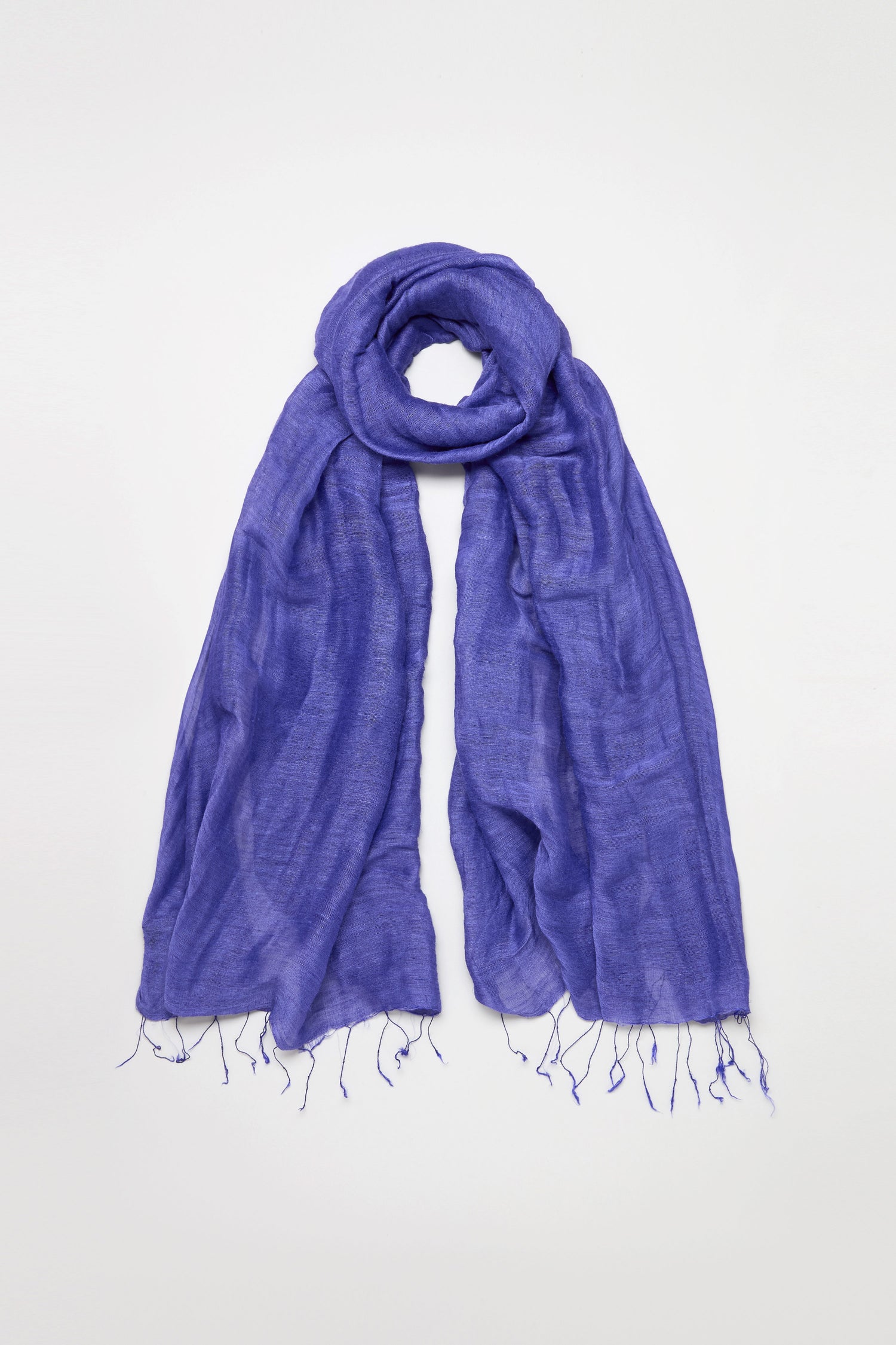 The Soft Linen Fringe Scarf, shown against a plain white background, is a lightweight purple accessory with a crinkled texture and fringed ends—perfect for effortless layering.