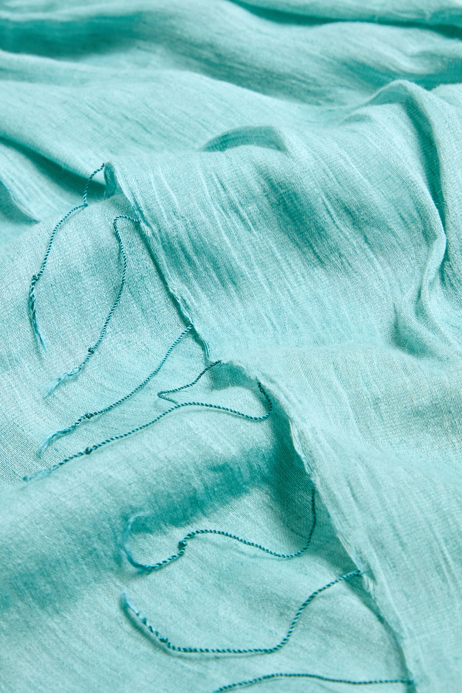 Close-up of the Soft Linen Fringe Scarf in light blue, featuring a slightly crinkled texture and frayed edges with loose threads—ideal for lightweight layering.