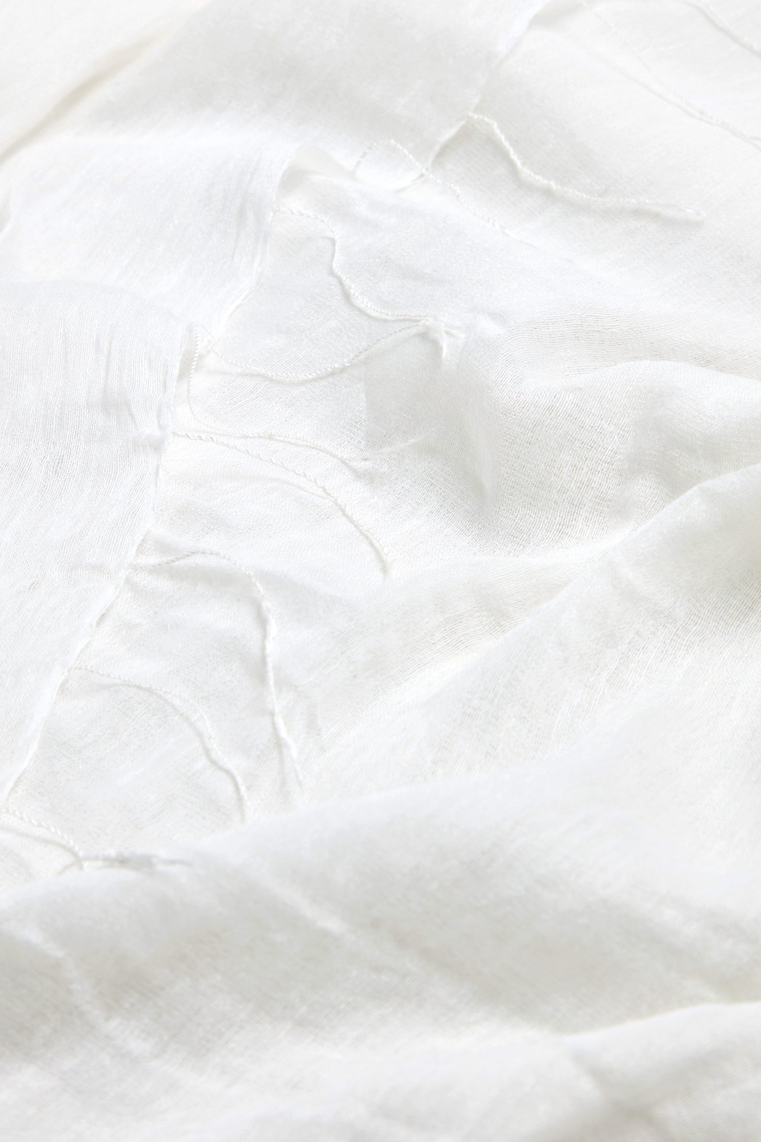 The Soft Linen Fringe Scarf features a textured surface with subtle wrinkles and visible thread lines, making it perfect for lightweight layering.