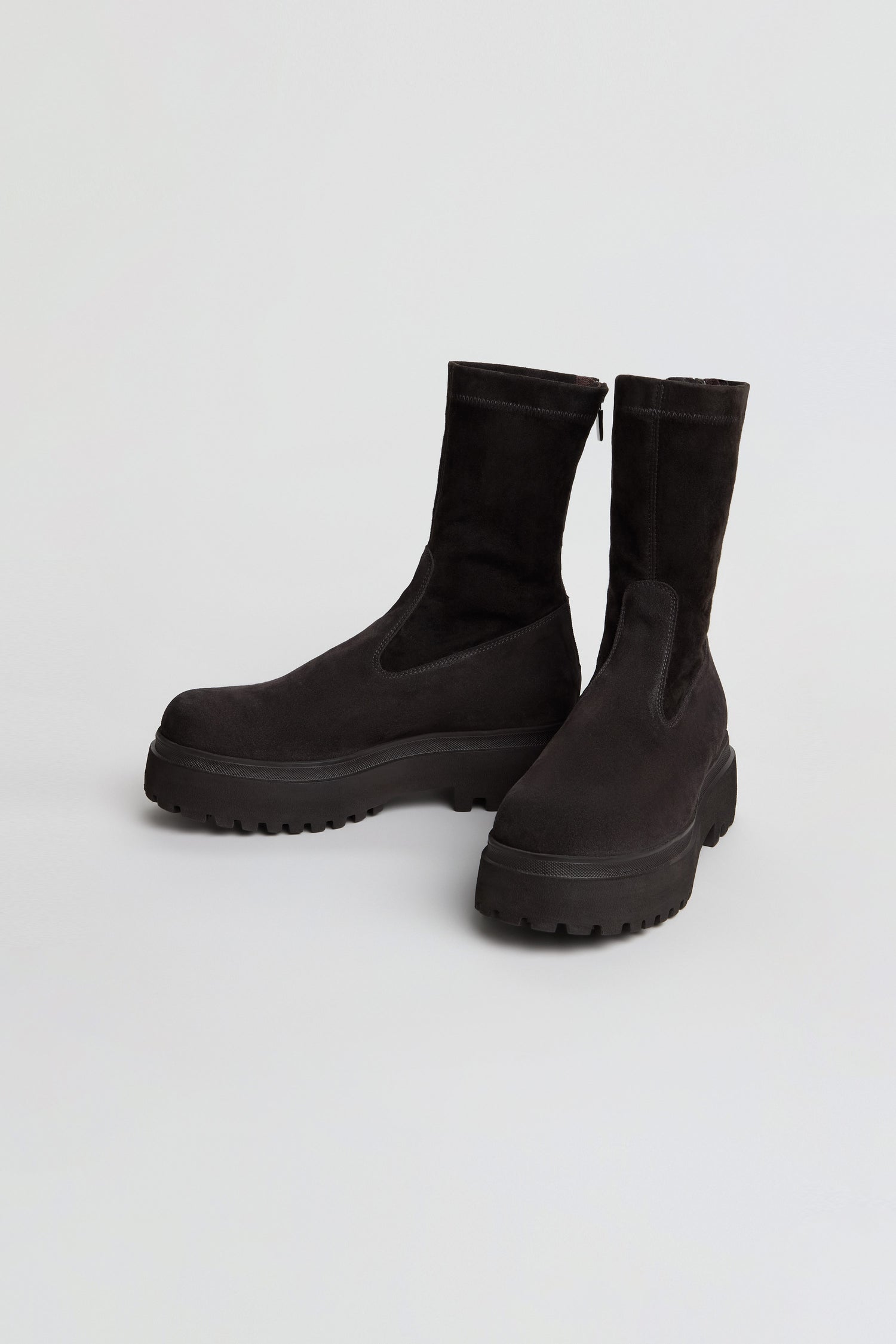 A pair of Short Stretch Suede Boots in black, featuring a mid-calf height and chunky rubber soles, displayed against a plain white background.