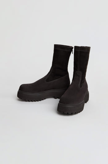 A pair of Short Stretch Suede Boots in black, featuring a mid-calf height and chunky rubber soles, displayed against a plain white background.