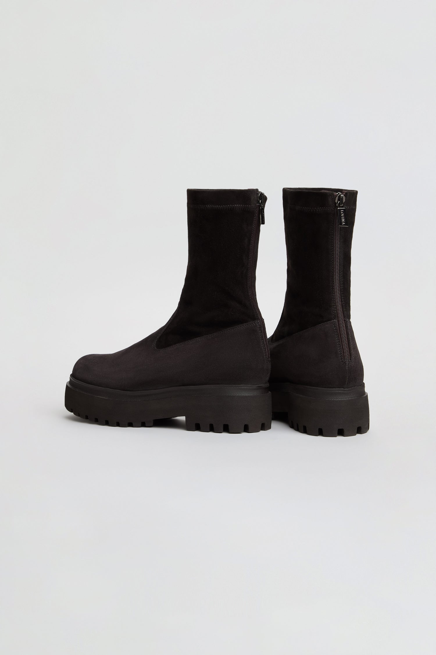 A pair of Short Stretch Suede Boots in black, featuring a mid-calf length, thick lug soles, and convenient back zippers, displayed against a plain white background. These boots effortlessly blend modern edge with classic style—the perfect choice to elevate any outfit.