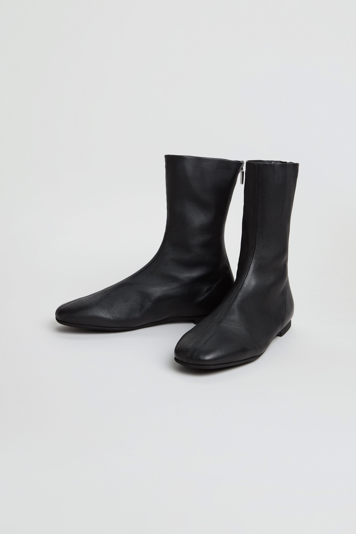 A pair of Slim Napa Leather Stretch Boots in black, featuring a mid-calf slim design with side zippers, displayed on a plain white background.