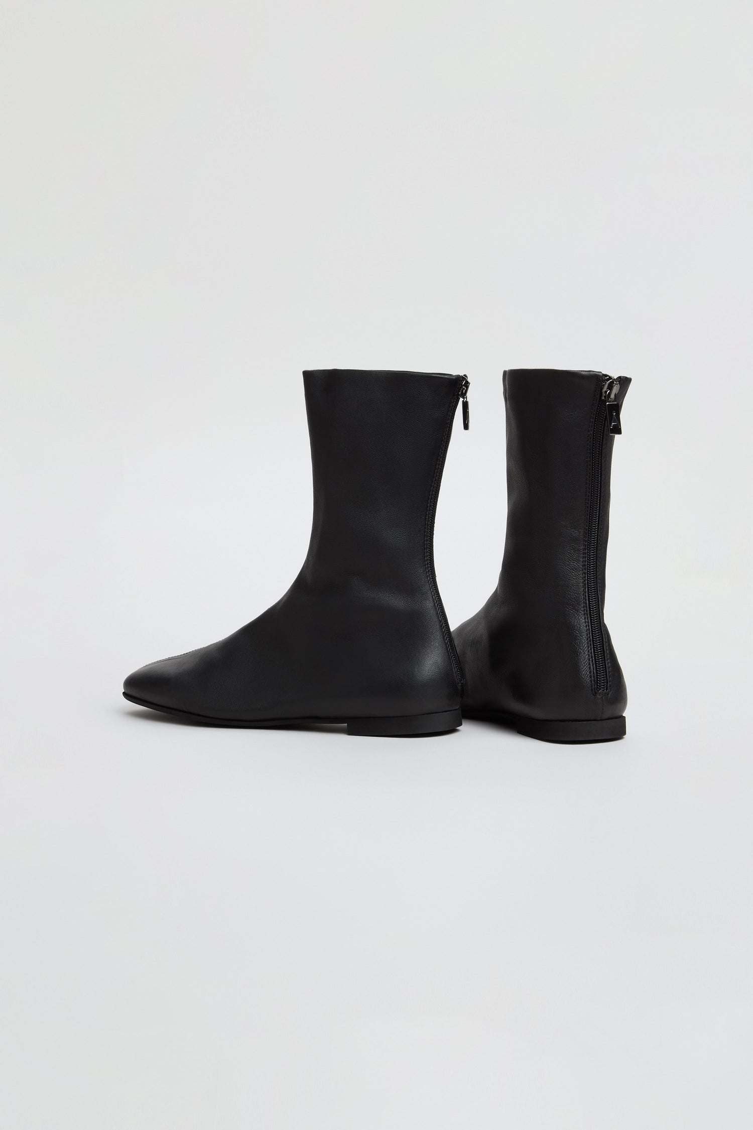 Pair of black Slim Napa Leather Stretch Boots featuring side zippers, crafted from smooth napa leather; one boot stands upright while the other is angled sideways, both displayed against a plain white background.
