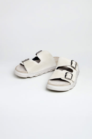 A pair of Double Buckle Suede Sliders handcrafted in Italy, featuring two adjustable buckle straps in suede, displayed on a plain white background.