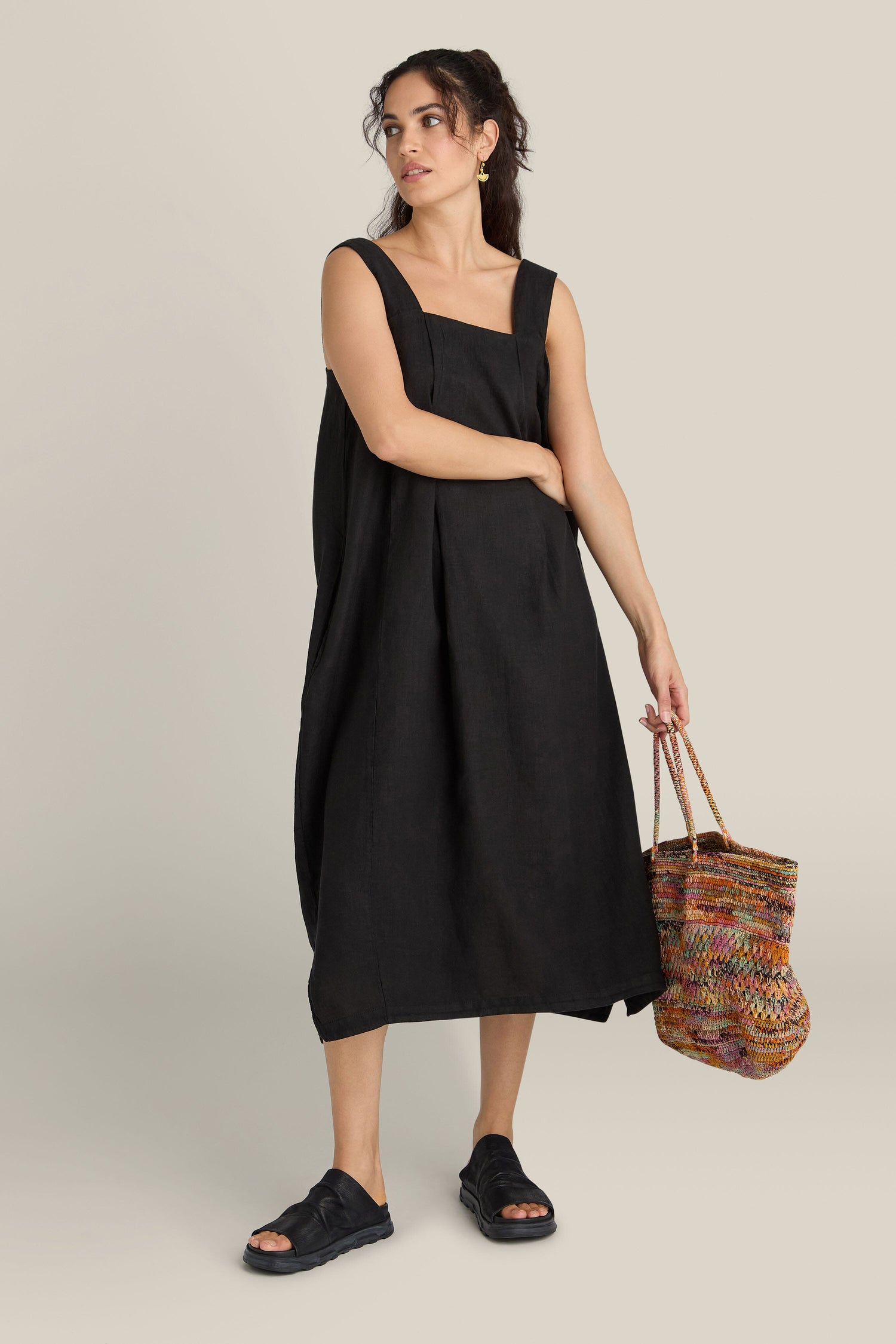 A woman in a black dress paired with the Crushed Leather Slider, showcasing exquisite Scandinavian design.