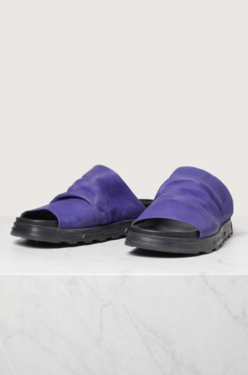 A pair of Crushed Leather Slider sandals with Scandinavian design on a marble surface.