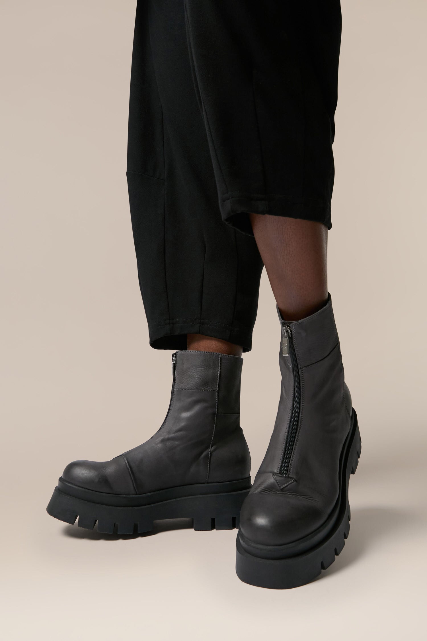 A woman in black pants and black Platform Zip Front Leather Boots, showcasing Italian craftsmanship and Danish design.