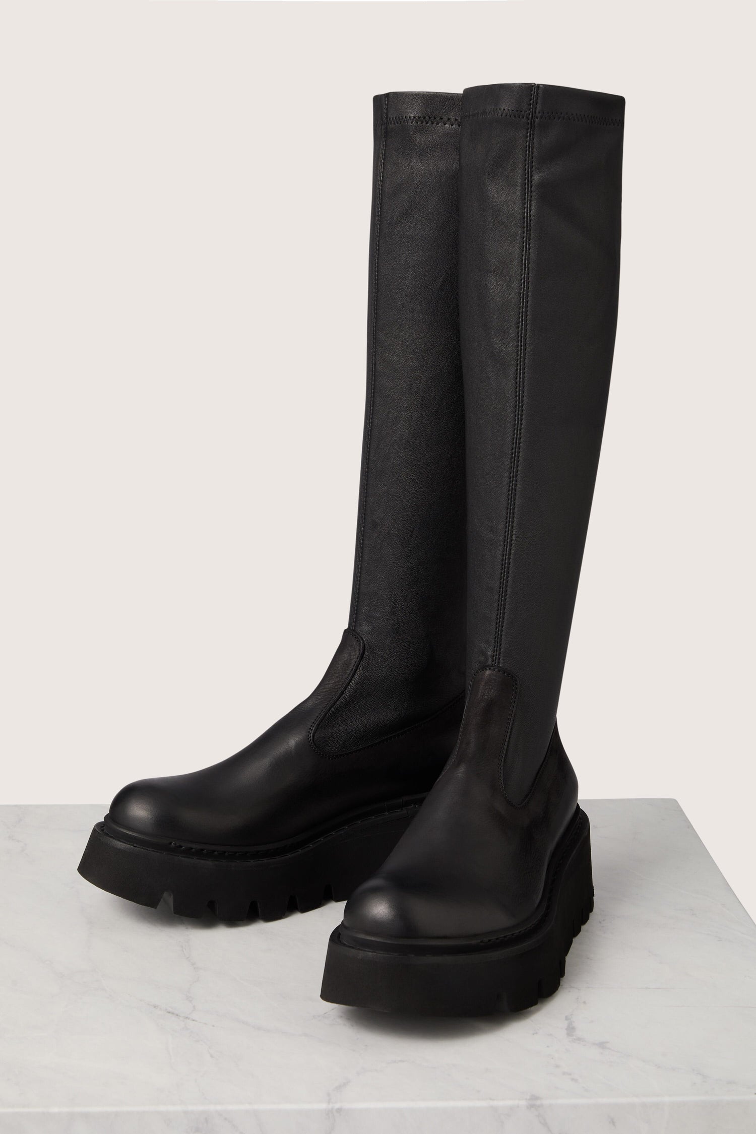 A pair of Long Stretch Leather Boots, showcasing Danish design and Italian craftsmanship, elegantly placed on a marble table.