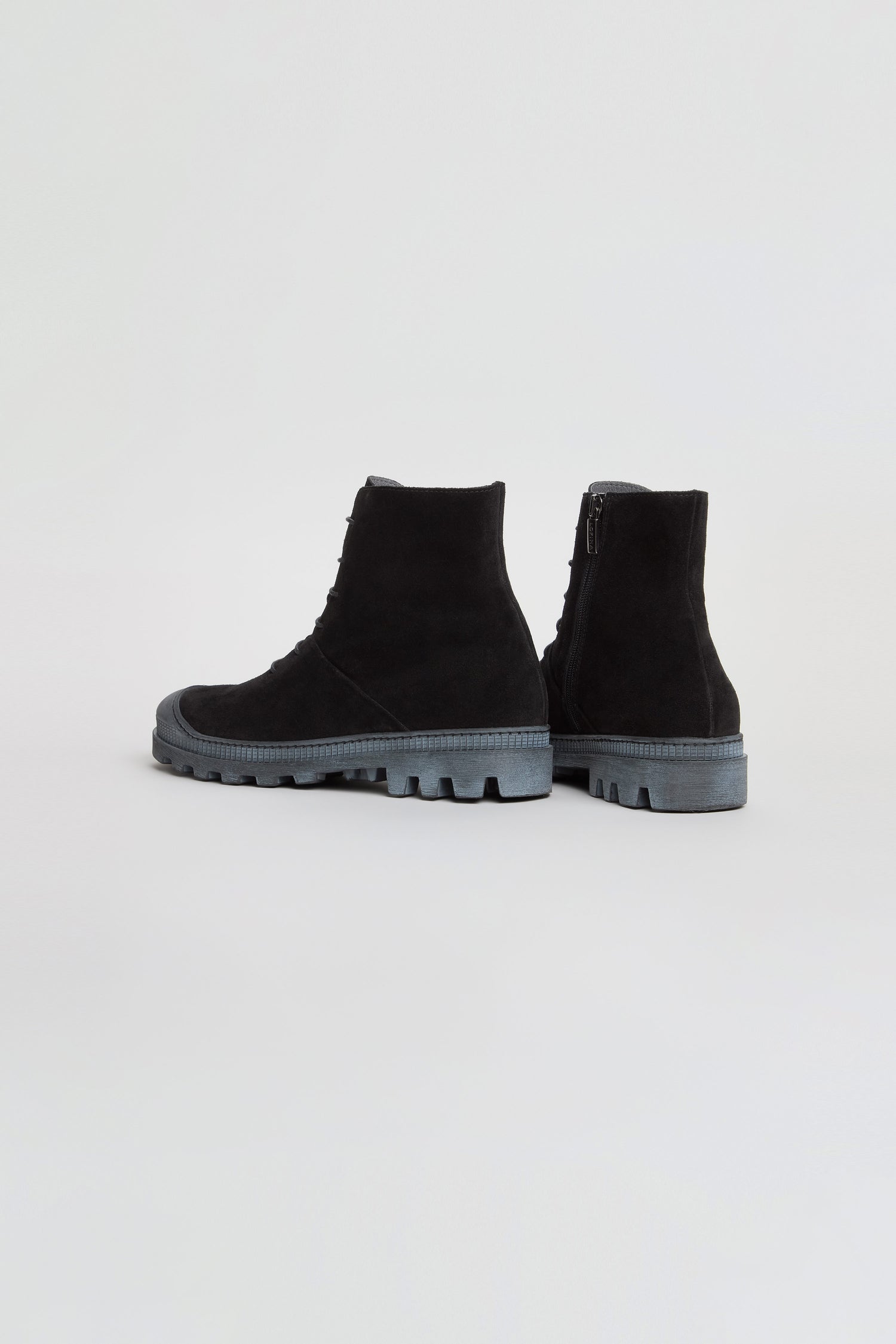 A pair of Lace Up Suede Boots in black, crafted with suede uppers and thick gray rubber soles, displayed against a plain white background. These chunky ankle boots offer a classic lace-up design that combines style with comfort.