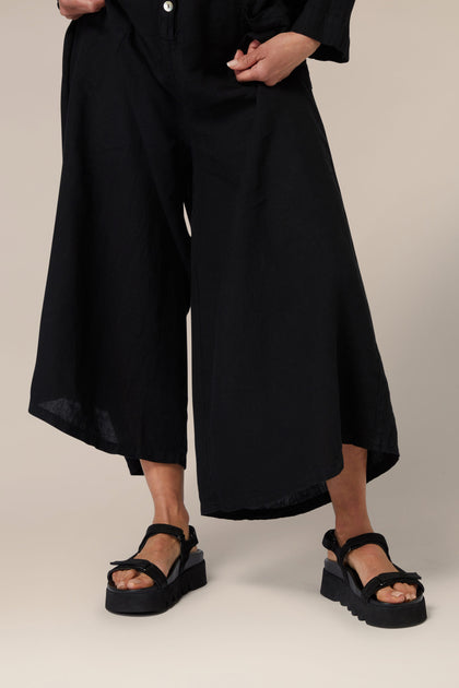 A person wearing black culottes with Scandinavian-designed Suede Velcro Sandals.