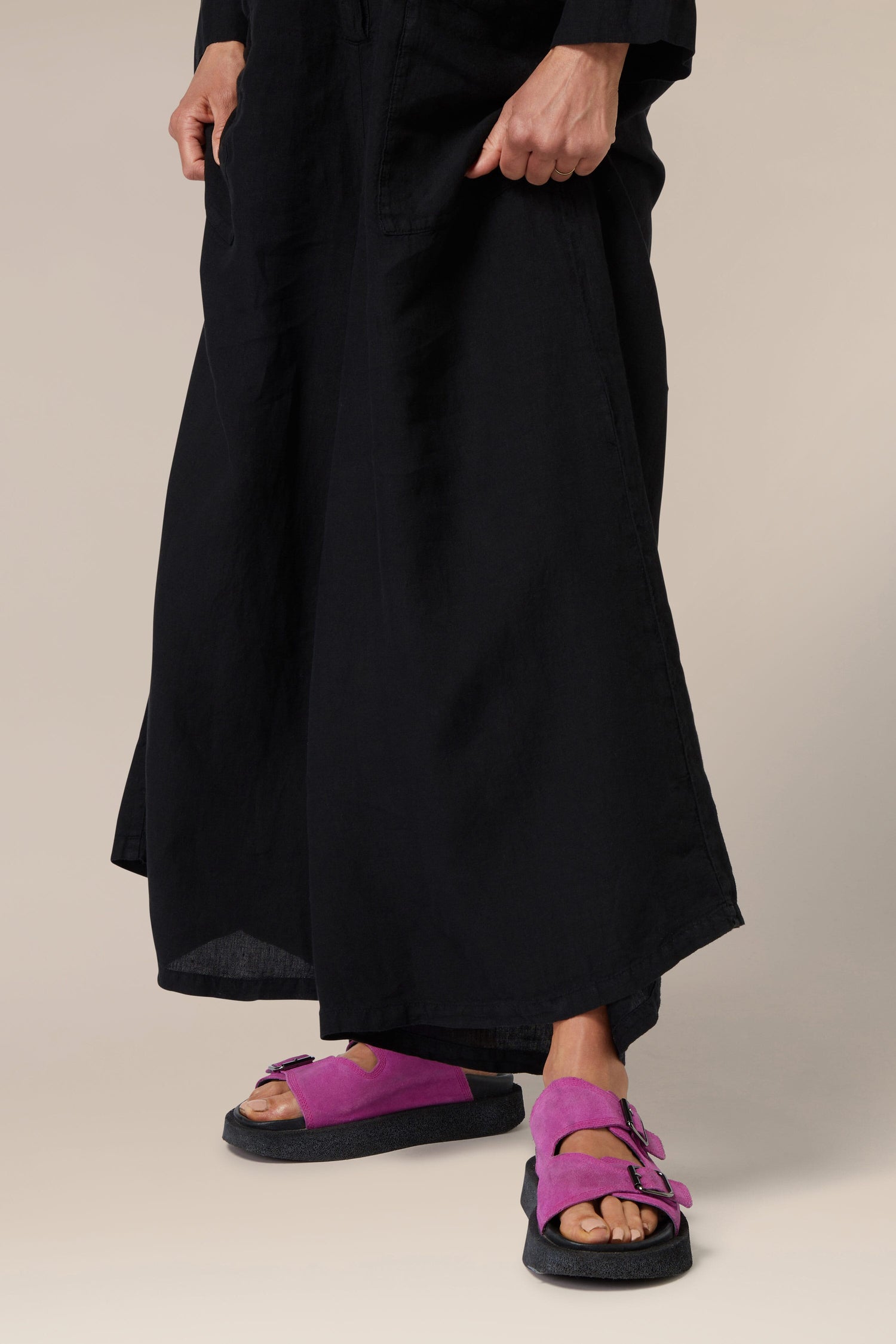 Person wearing black wide-leg trousers and purple Suede Double Buckle Slider sandals.