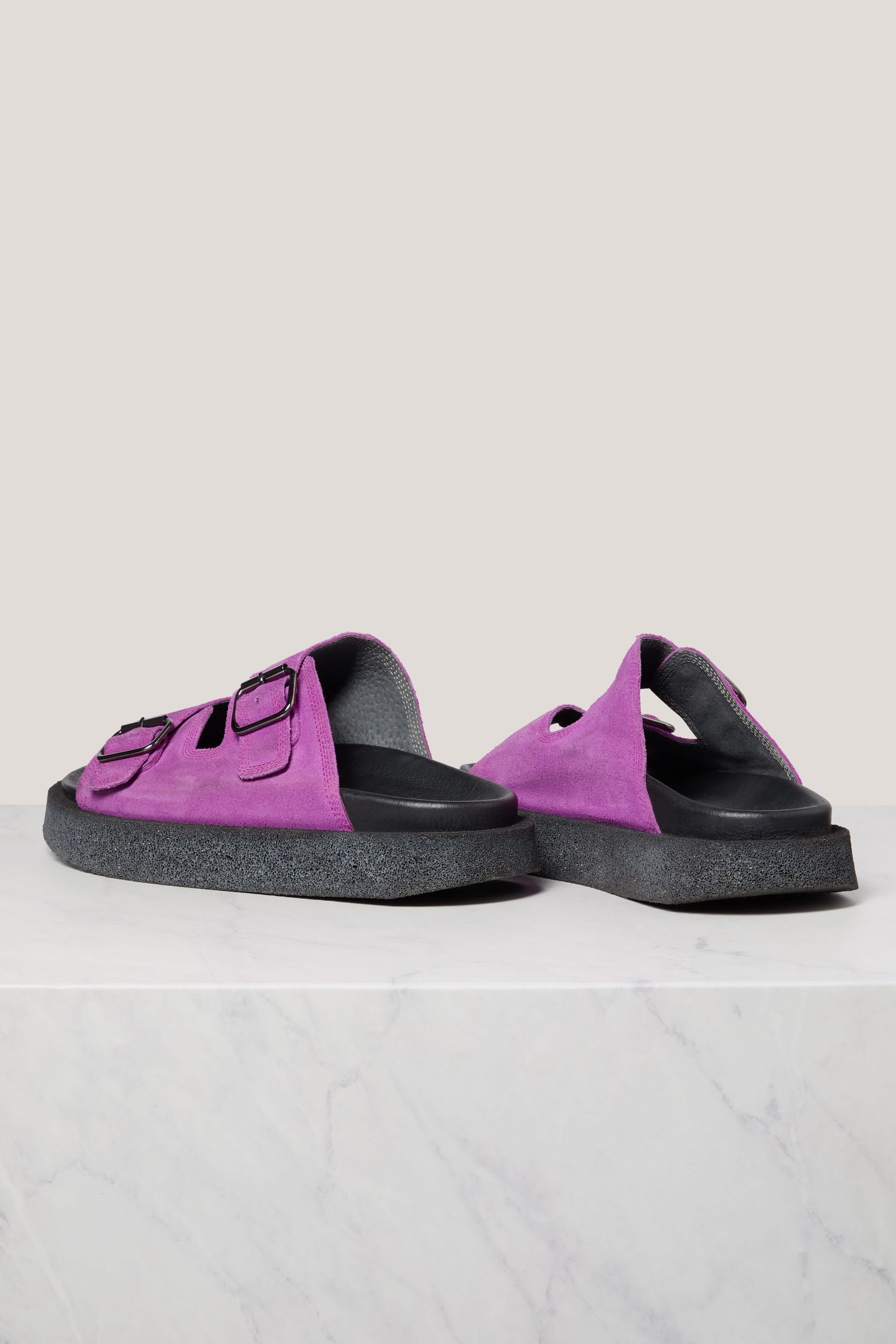 A pair of purple Suede Double Buckle Sliders on a white surface against a grey background.