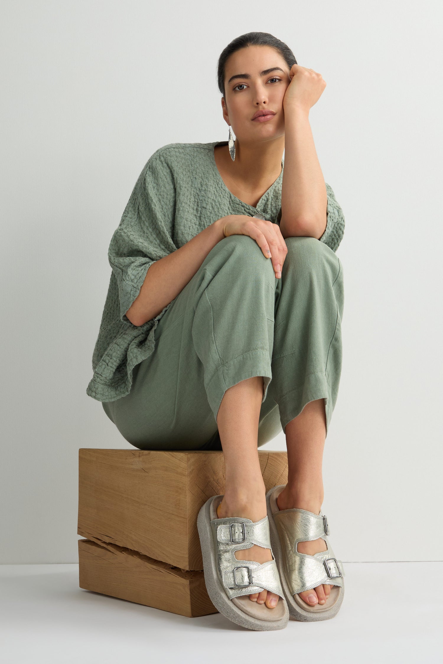 Person wearing wide-leg jeans, a striped shirt, and Sahara exclusive Metallic Silver Double Buckle Leather Sliders standing against a white background.