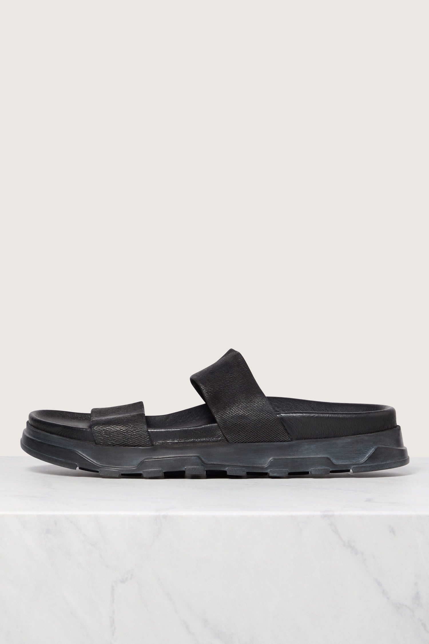 A single black Gucci Stretch Leather Slider sandal displayed on a white marble surface.
