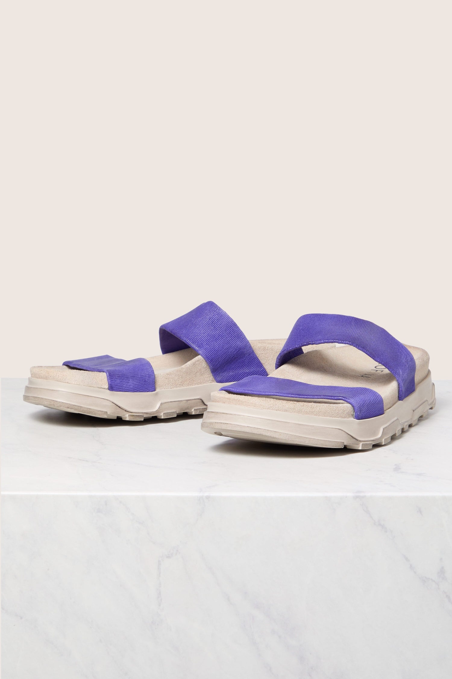 A pair of purple Strappy Bimini Sandals on a marble surface with a neutral background, embodying Scandinavian design.