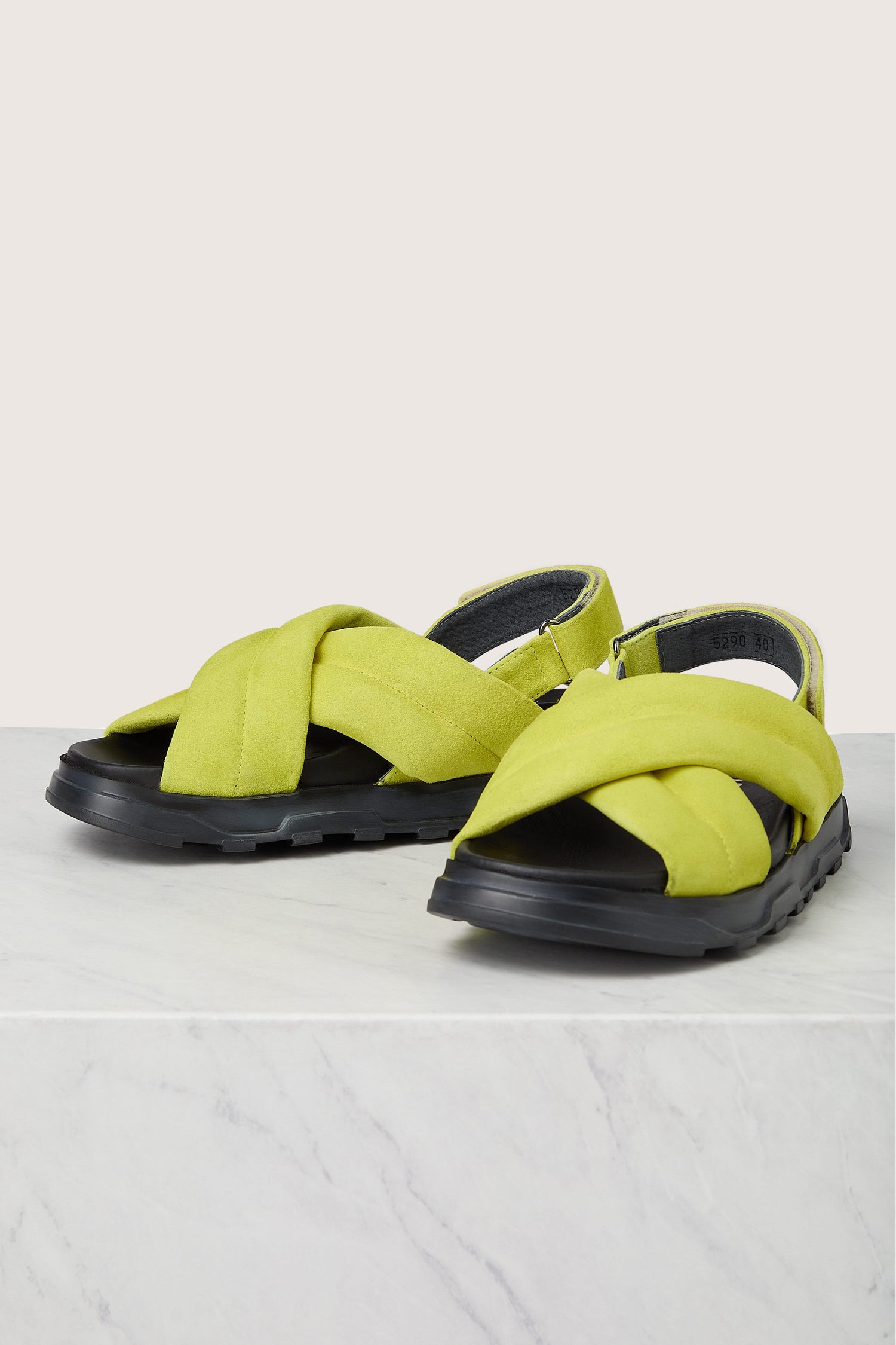 Pair of green Suede Crossover Sandals with oversized bows on a marble surface, showcasing Italian construction.