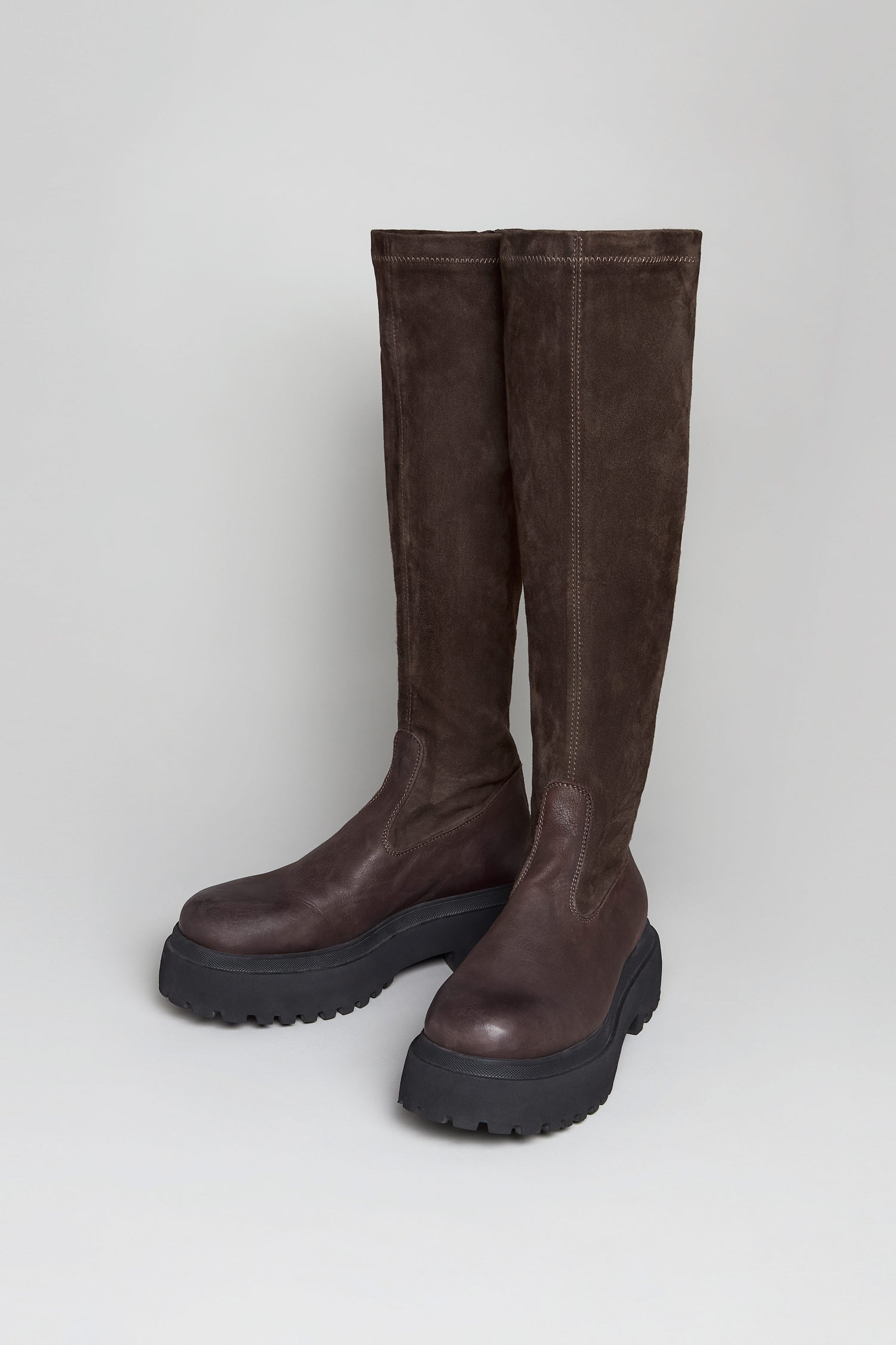 The Chocolate Long Stretch High Knee Suede Boots, featuring chunky black platform soles and crafted from suede and leather, stand upright against a plain light background.