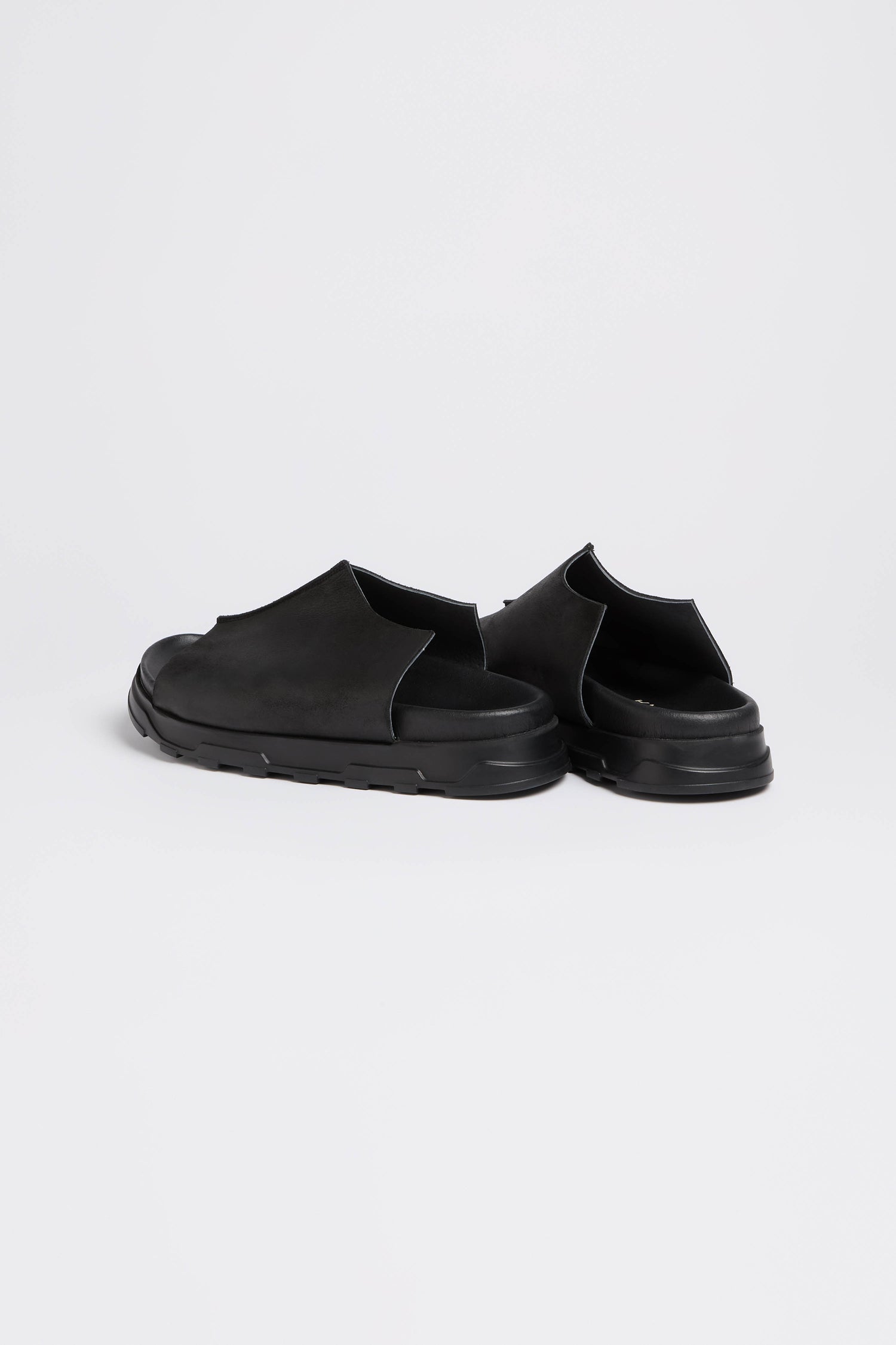 Seam Leather Sliders feature a sleek, modern design with cushioned soles, epitomizing contemporary minimalism against a plain white background.