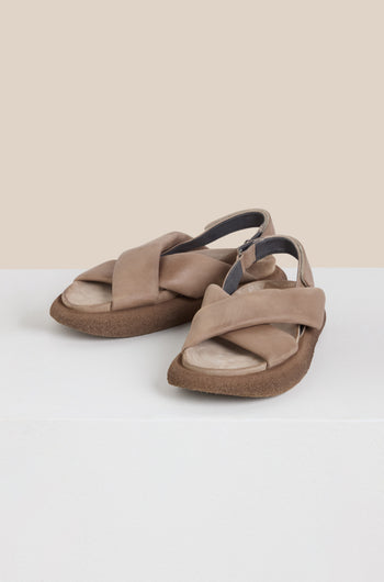 Crossover Leather Sandals: Beige crossover design with wide crisscross leather straps and thick soles shown on a white surface against a light beige background, highlighting Scandinavian craftsmanship.