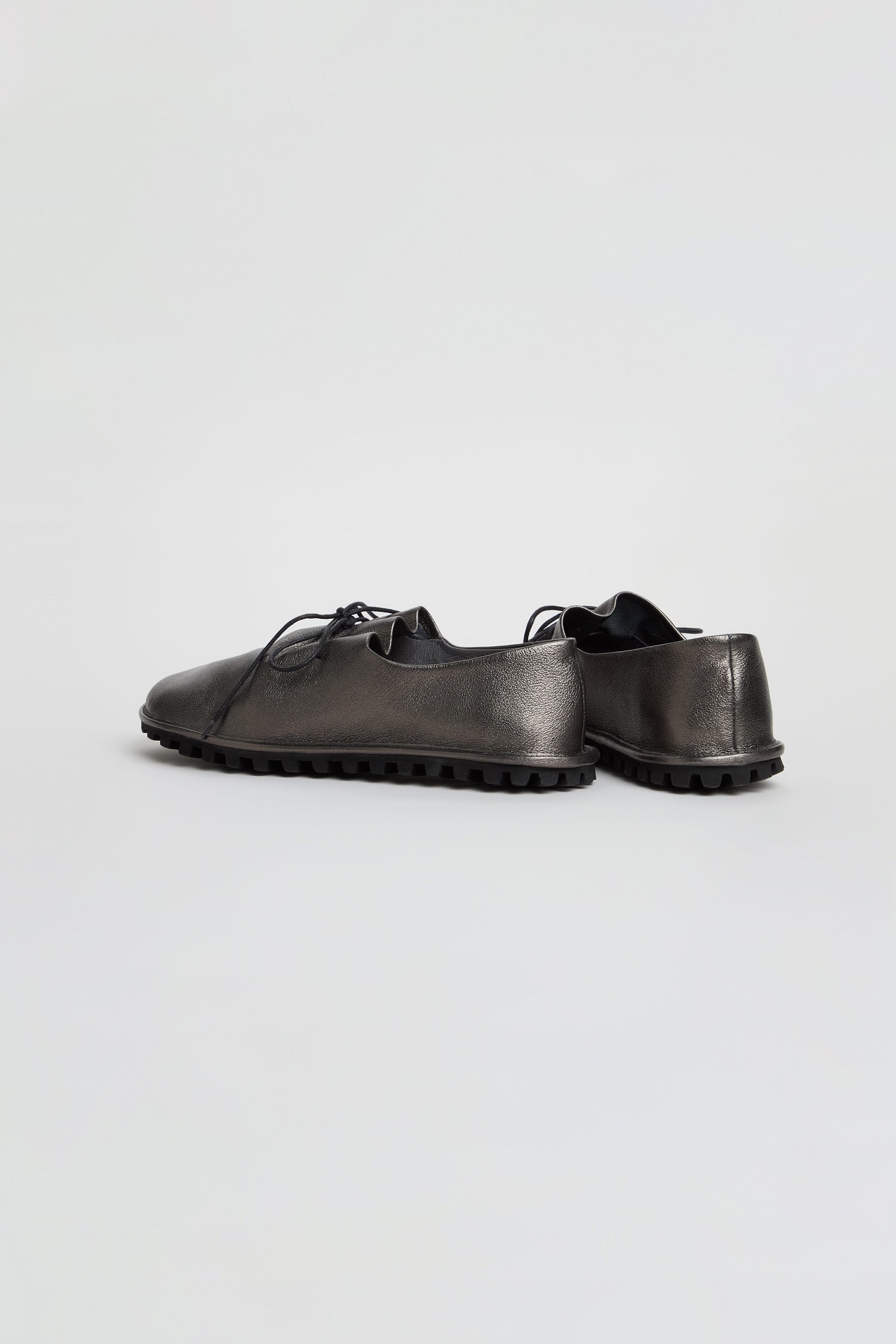 Pair of Hematite Crushed Leather Lace Up Shoes in black, featuring low-top design, textured rubber soles, and a striking metallic leather finish, placed on a plain light background.