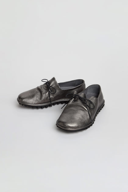 A pair of Hematite Crushed Leather Lace up Shoes, handmade in Italy, featuring a striking metallic leather finish and textured rubber soles, displayed on a white background.